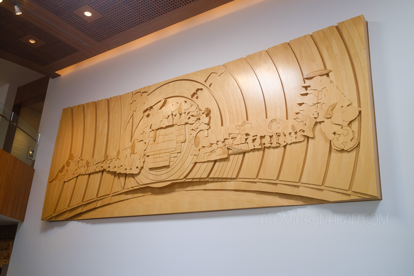 A large layered wood sculpture featuring images of Snoopy through the years.