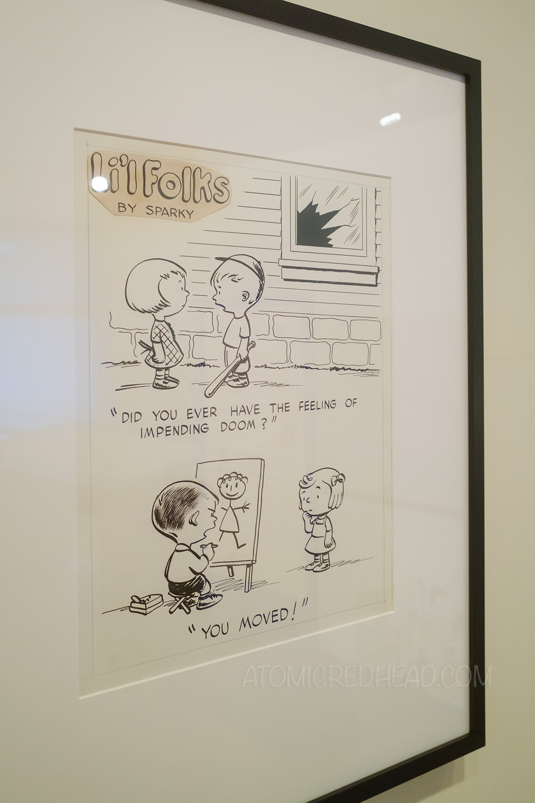 Original page from Schulz's earlier comic Li'l Folks, one panel features a boy holding a baseball bat with a broken window behind him, he speaks to the little girl next to him "Did you ever have the feeling of impending doom?" below a little boy draws a stick figure of a little girl in front of him, the text reads "You moved."