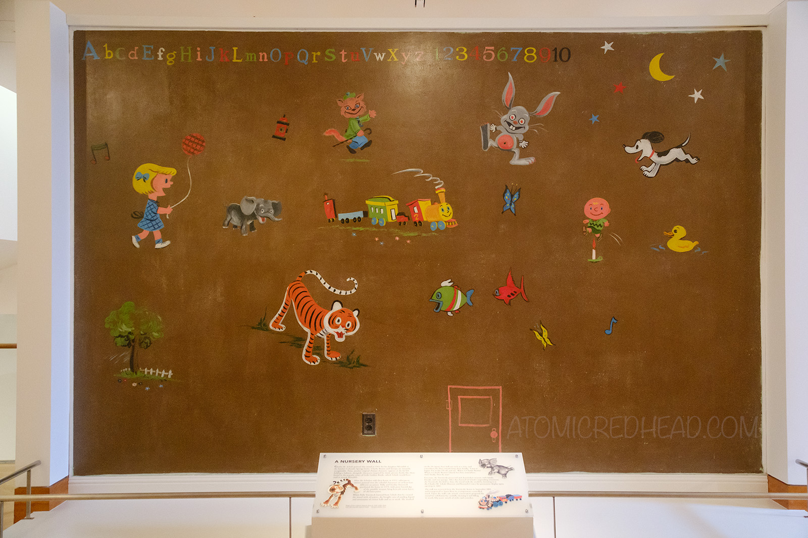 A large mural featuring Patty with a balloon, elephant, tigers, rabbit, Snoopy, moon and stars, Charlie Brown, train, duck, and fish.