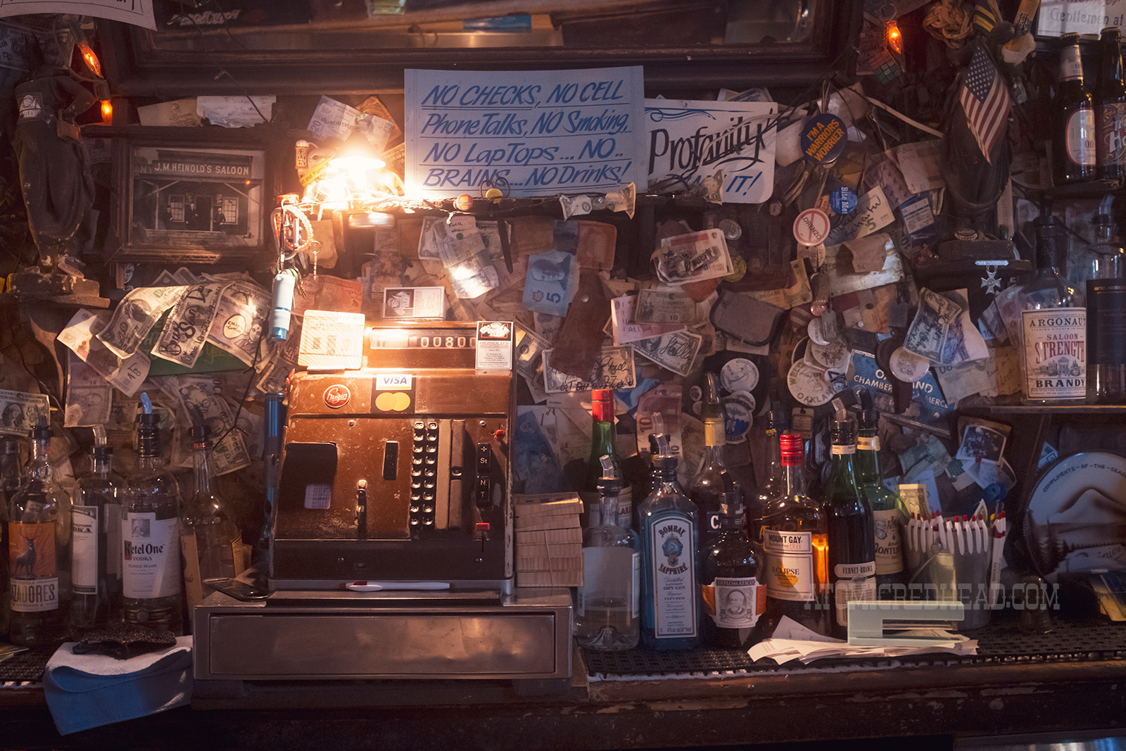 A vintage cash register sits behind the bar, and above it a sign reads "No checks, no cell phone talks, no smoking, no laptops...no brains, no drinks!"