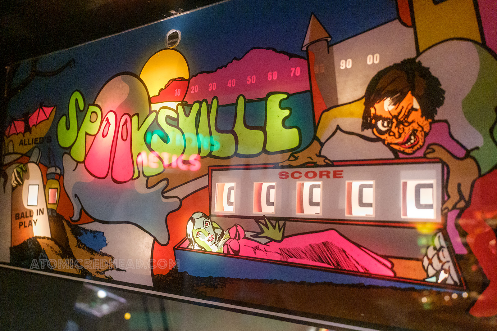 Scoreboard for Spooksville which features a woman in a casket, tombstones, and an Igor like character with a hunchback.