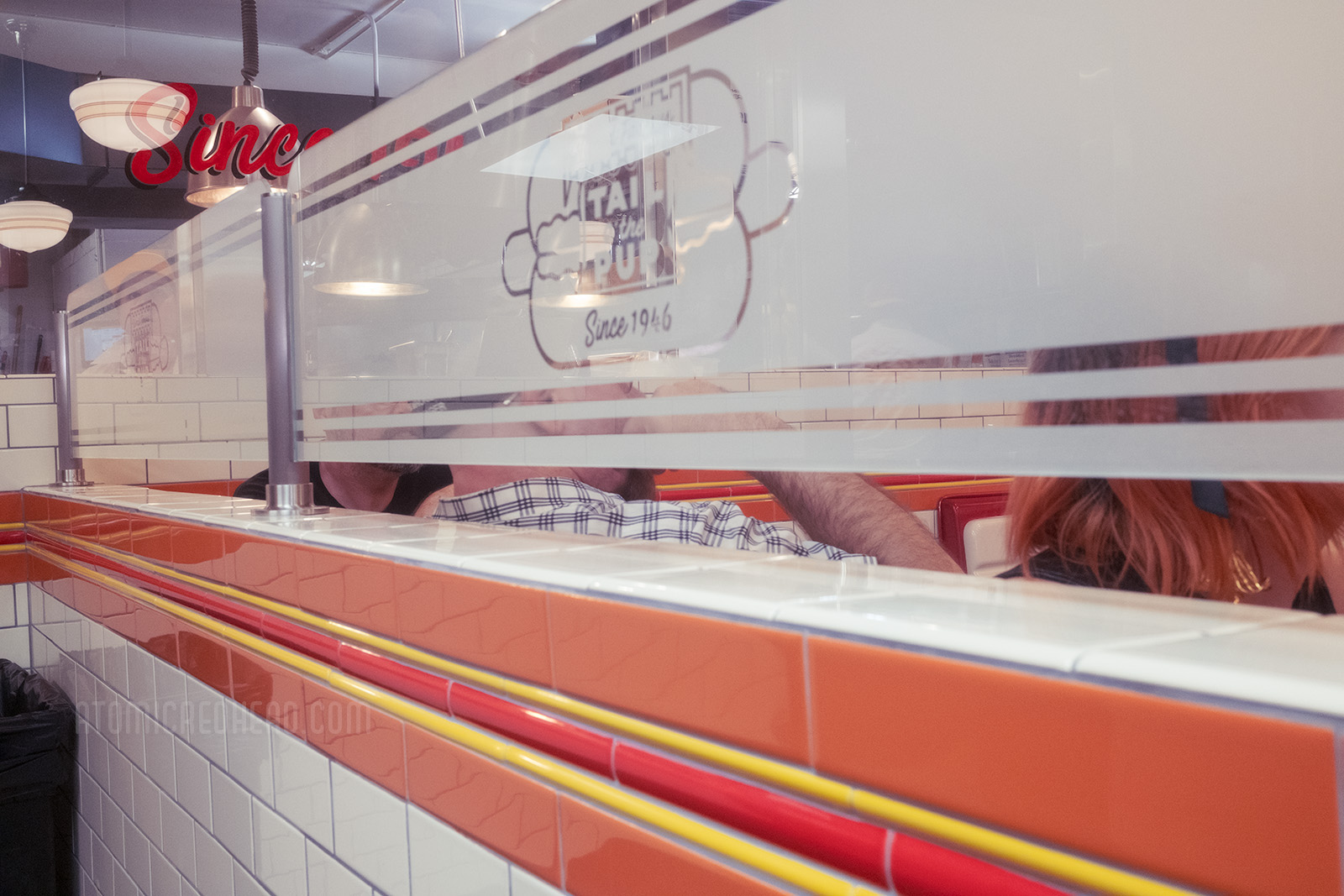 Tile work inside emulates a hot dog, with light brown, yellow, red, yellow, light brown tiles.