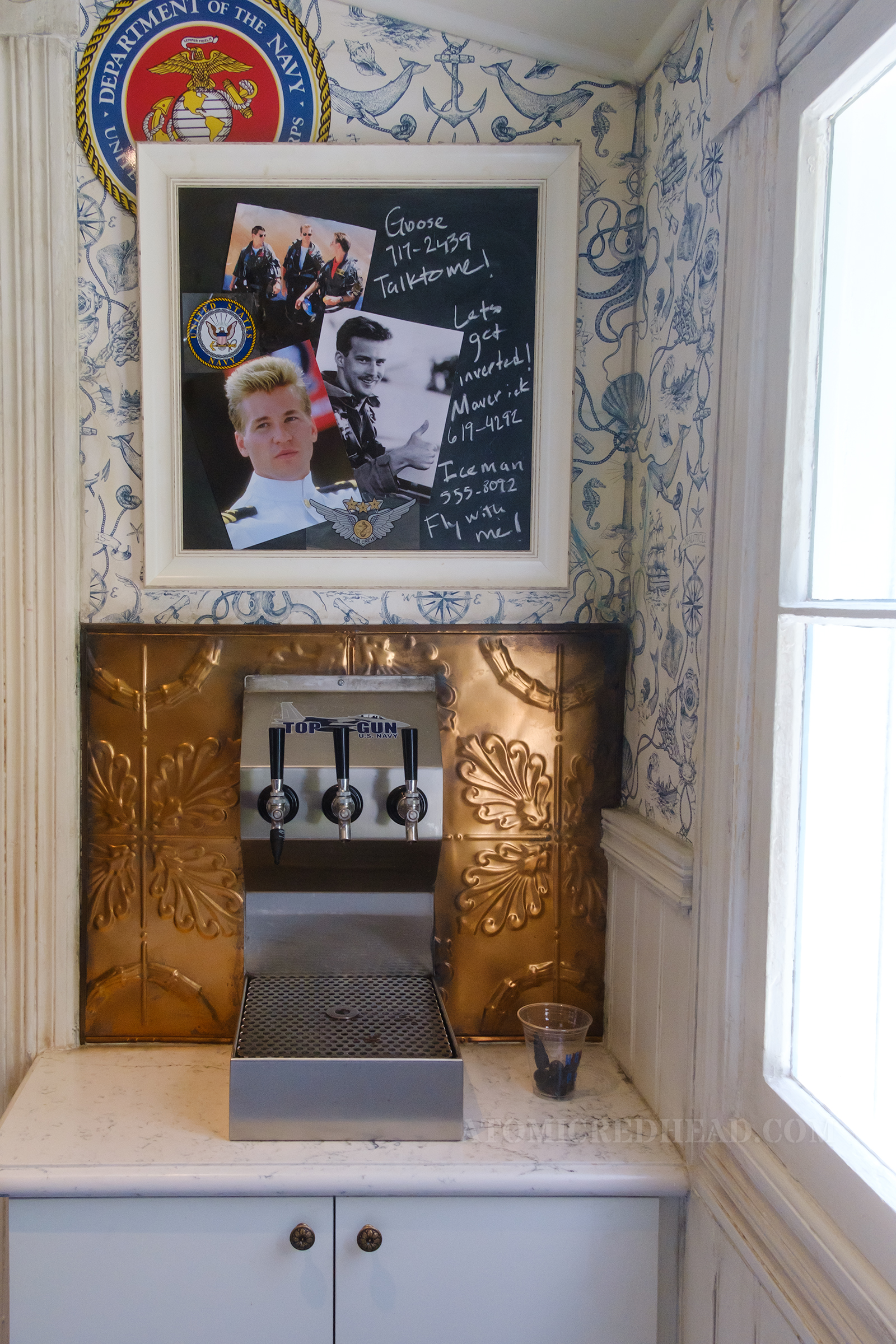 Pictures of Goose, Maverick, and Iceman hang on a chalkboard along with their phone numbers, next to Goose reads "Talk to me," next to Maverick's reads "Let's get inverted" and next to Iceman's it reads "Fly with me"