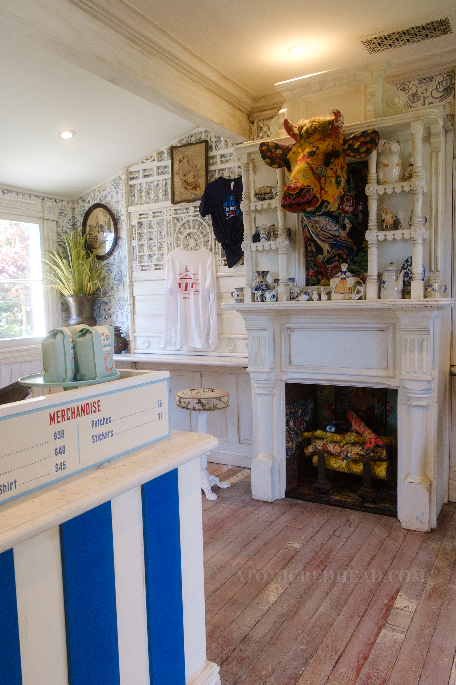 Fireplace of the house features a fake cow head above, and various knick-knacks. 