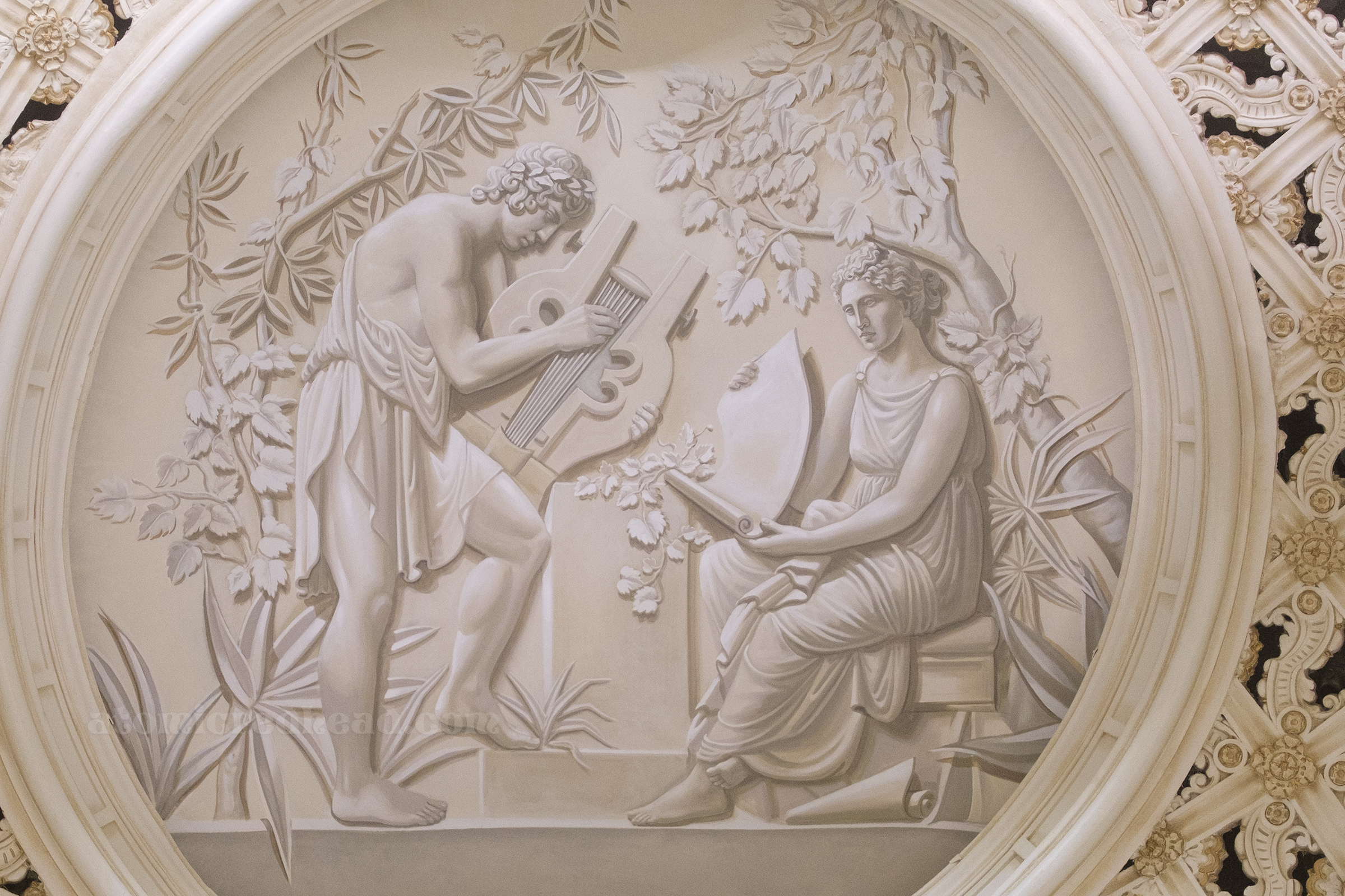 A mural of two persons in a Greek style, one holds a scroll, the other holds a lyre.