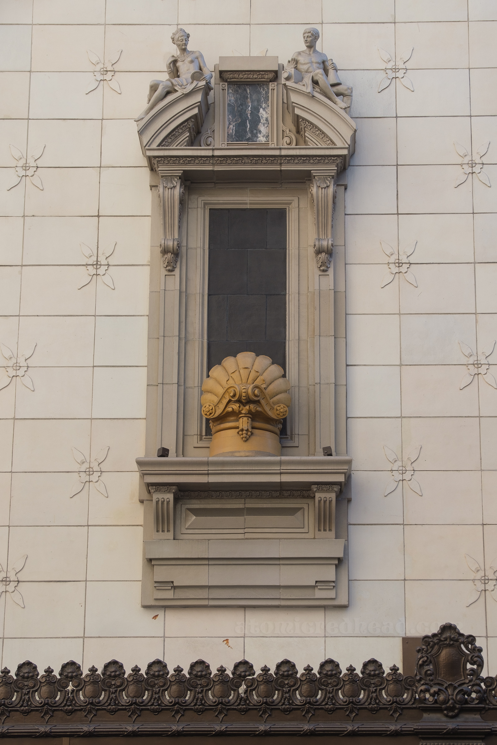 Detailed view of a window on the side, that features two sculptures of a man and a woman.