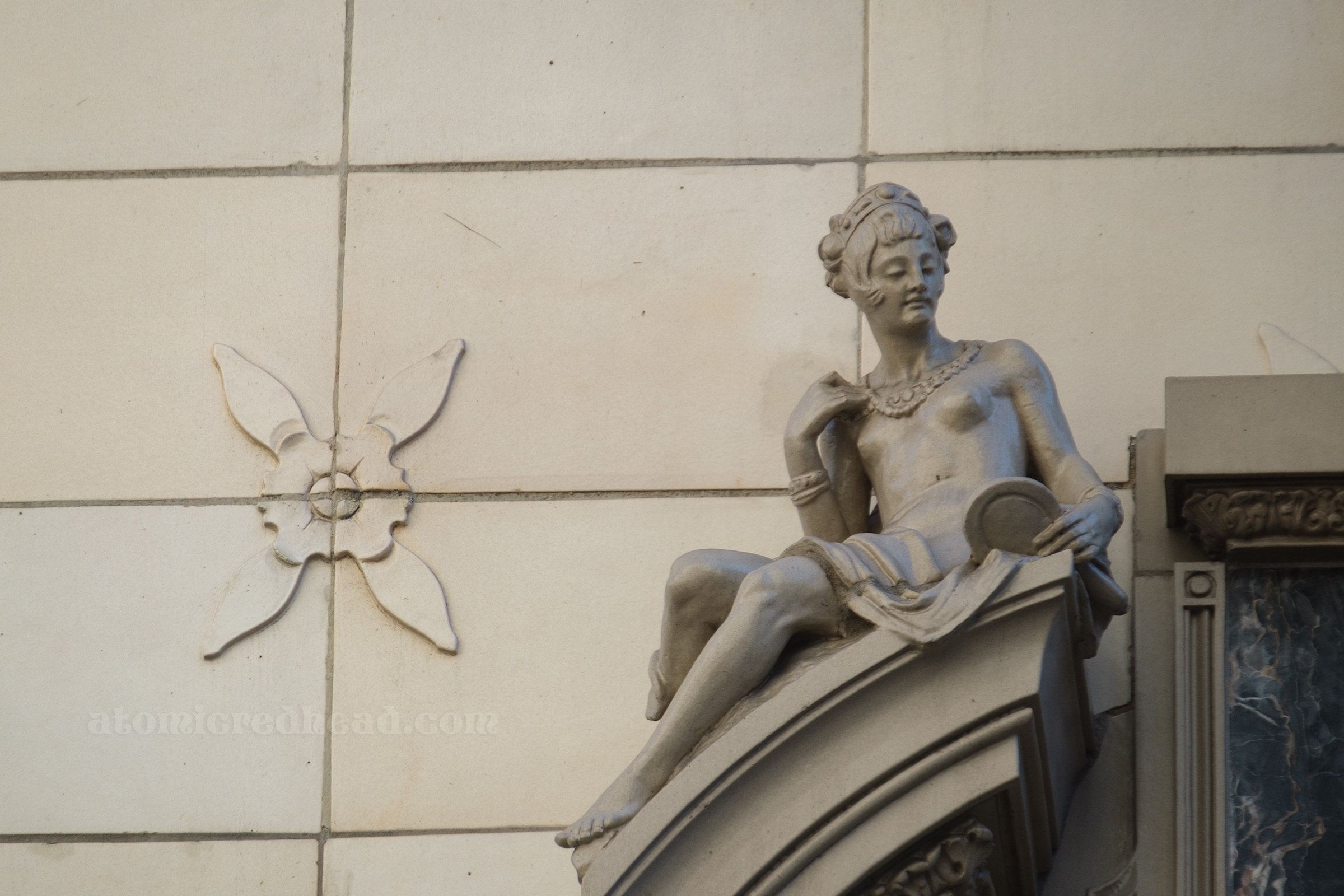 Close-up of the female sculpture, she holds a small mirror.