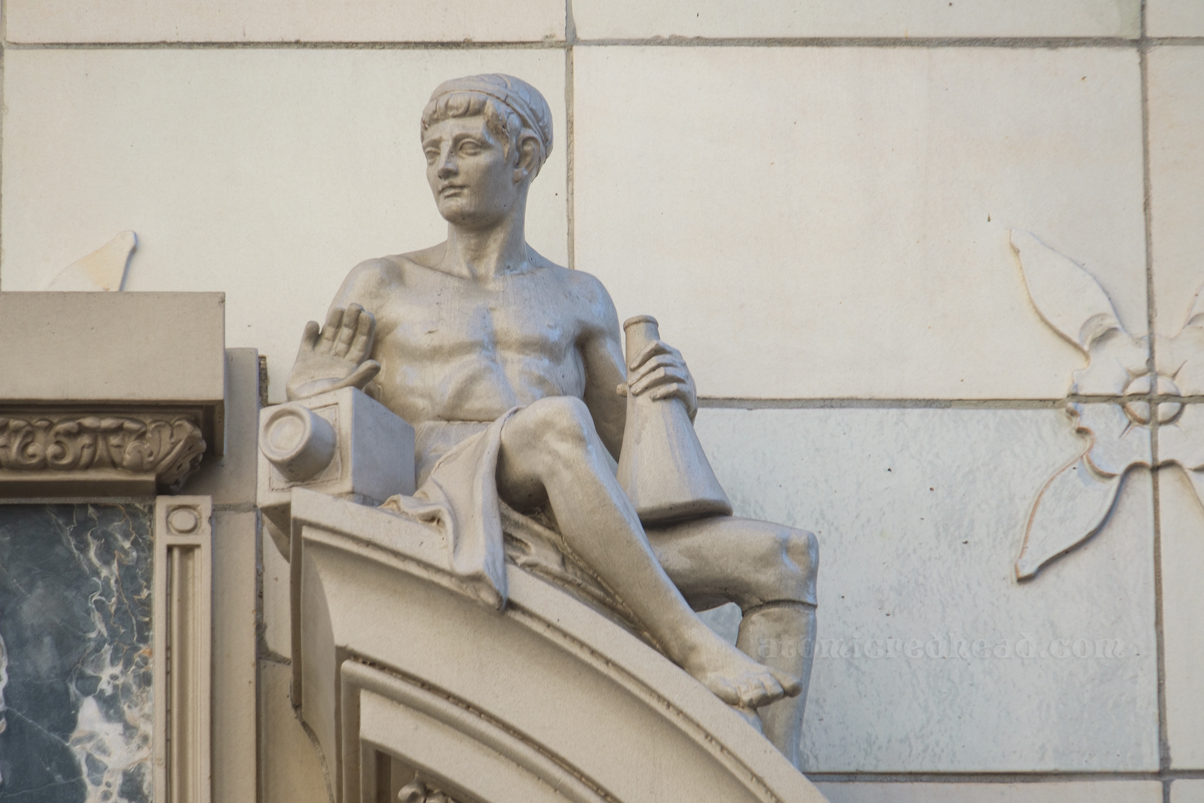 Close-up of the male sculpture, he holds a camera and a megaphone.