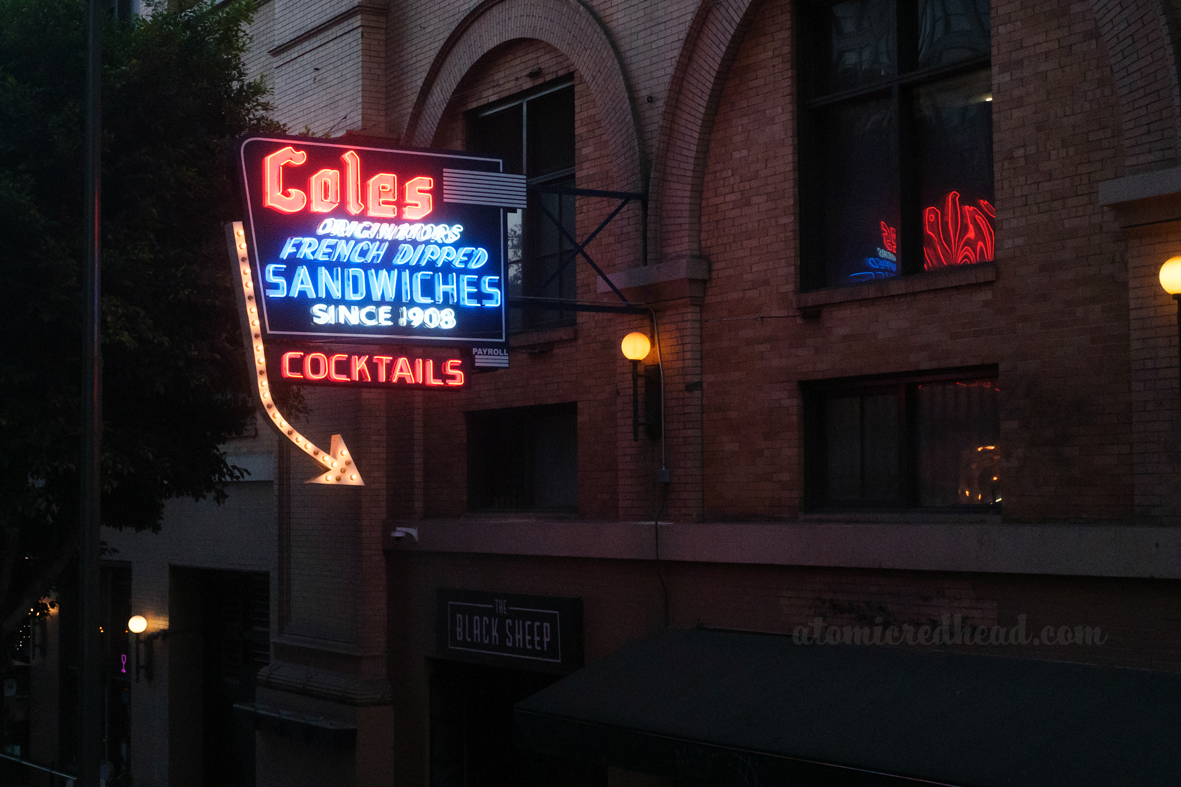 A red, white and blue neon sign reads "Coles Originators French Dipped Sandwiches Since 1908 Cocktails"