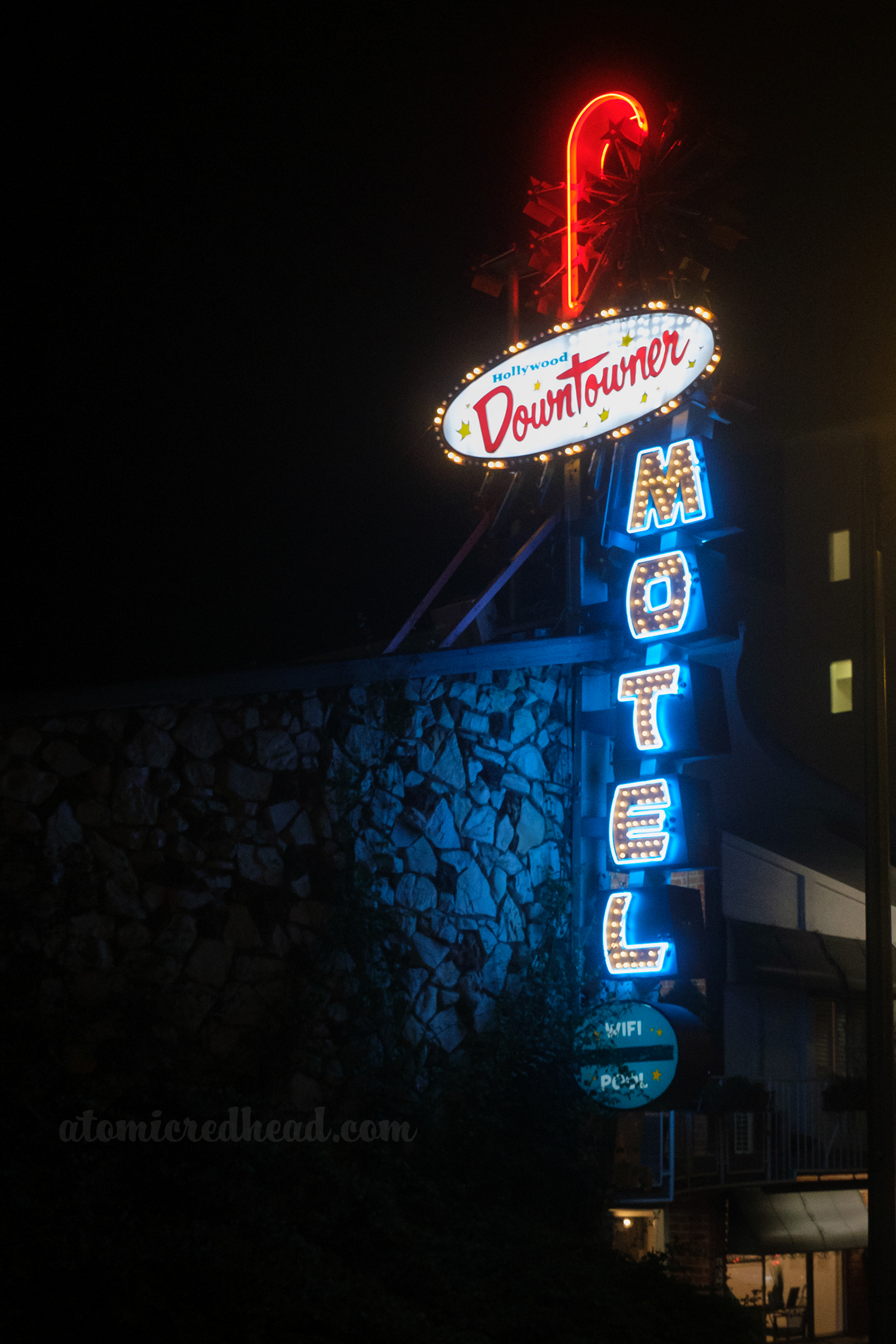 A combination bulb, neon, and backlist plastic sign for the Hollywood Downtowner Motel. "Hollywood Downtowner" is in backlit plastic, with "Motel" being edged in blue neon and the inside bulbs.