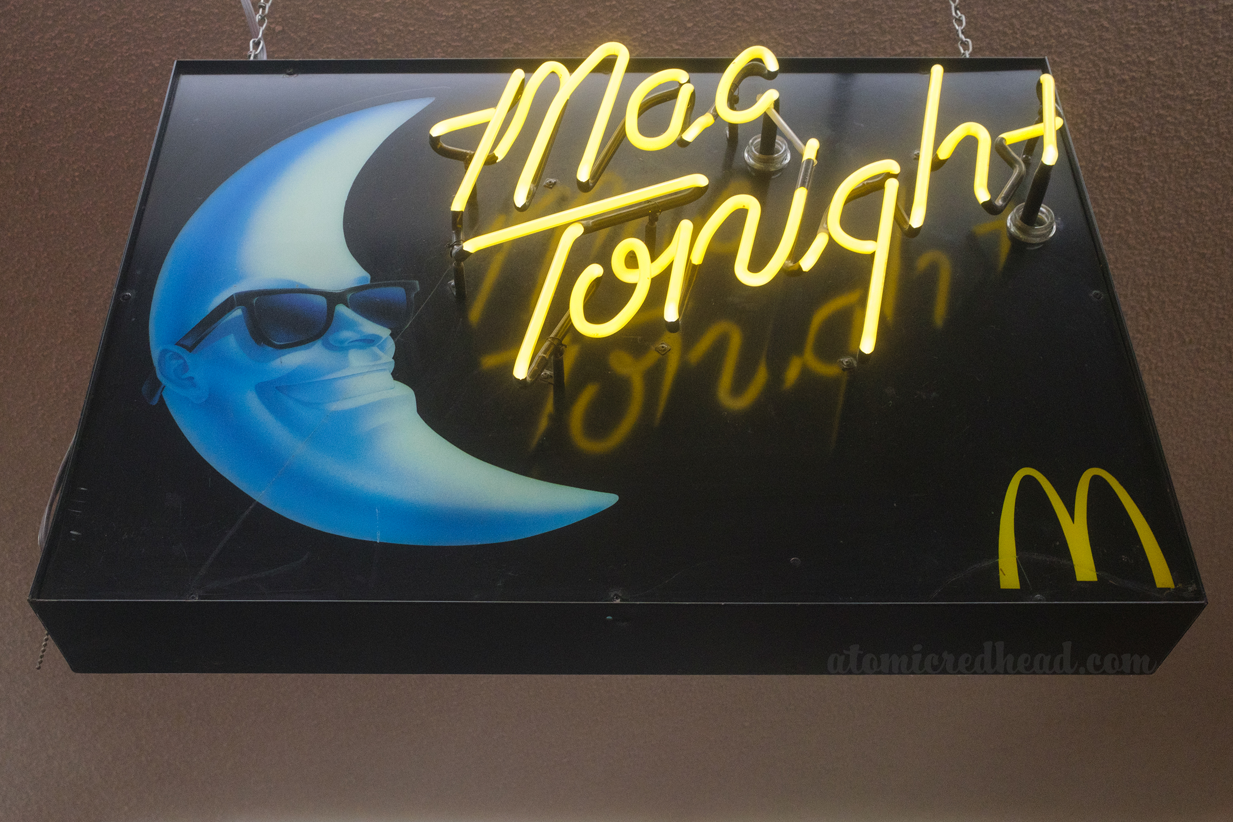 Neon sign reading "Mac Tonight" in yellow neon script and an image of the moon faced, sunglass wearing Mac.