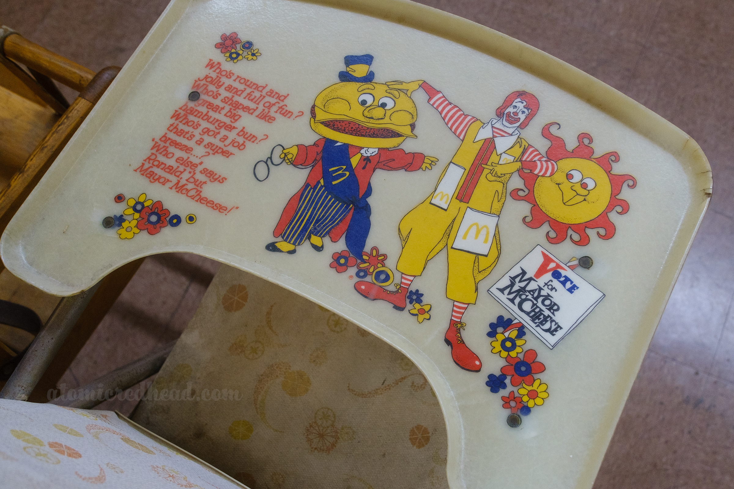 The tray of a high chair features Ronald and Mayor McCheese, with text reading "Who's round and jolly and full of fun? Who's shaped like a great big hamburger bun? Who's got a job that's a super breeze...? 'Who else,' says Ronald, 'but Mayor McCheese!" and a sign reading "Vote for Mayor McCheese"