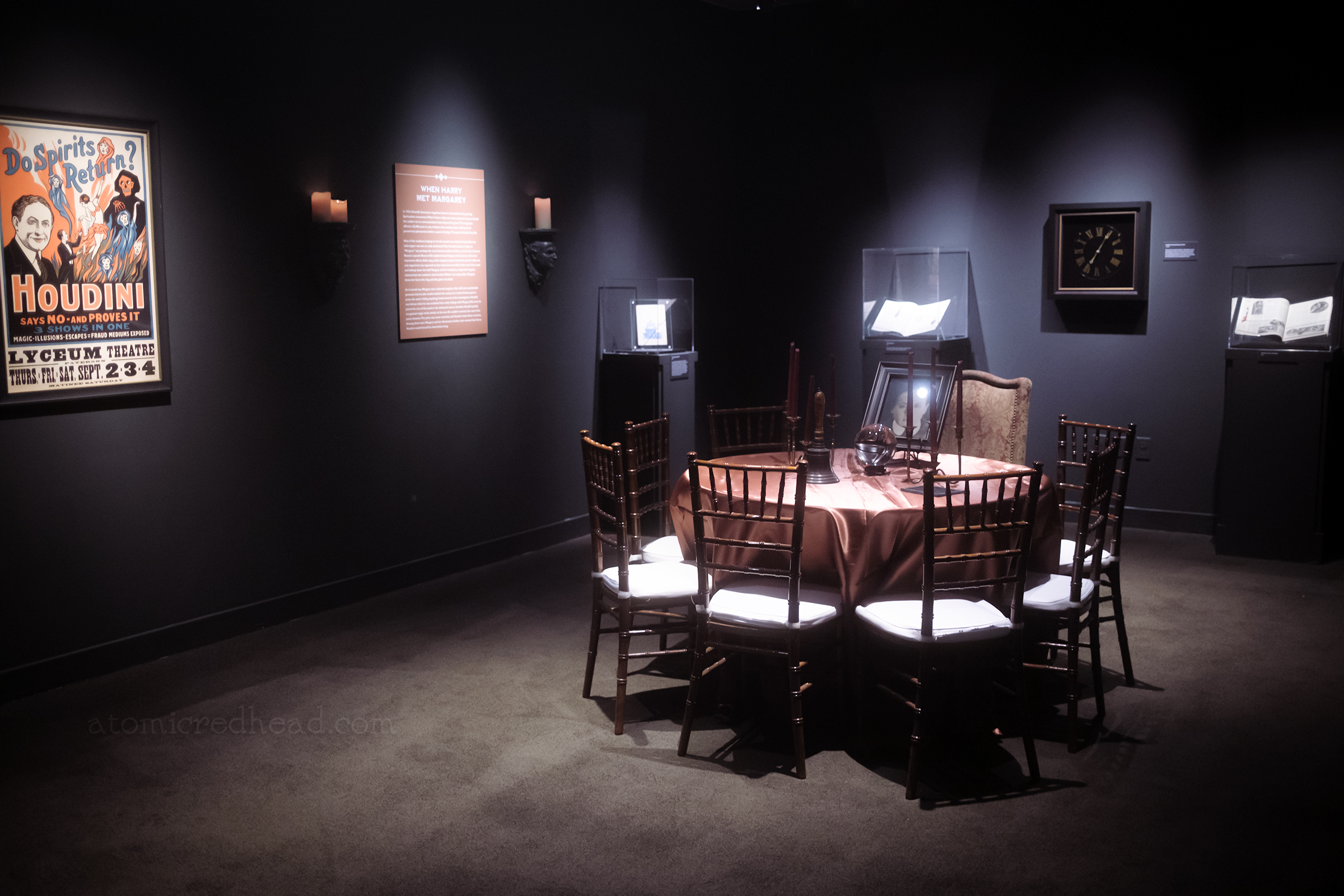 A round table sits in the middle of a room, and hold a photograph of him, a crystal ball, a bell, and candles.