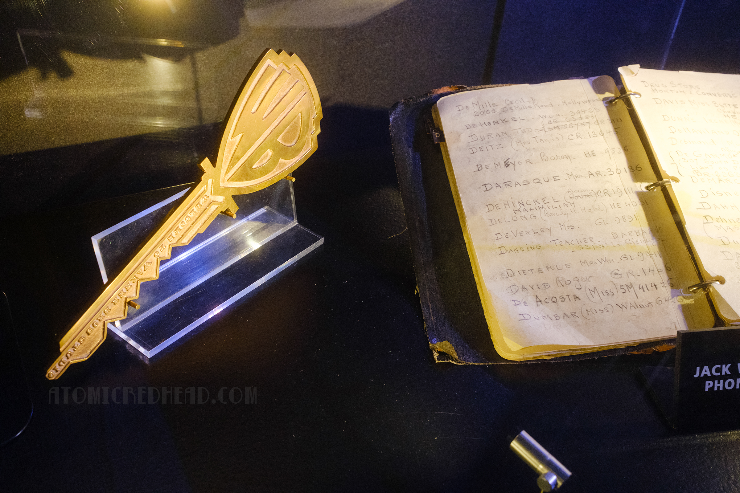 A large "Key to the Studio" rests next to a phone book that belonged to Jack Warner. The top of the large key features the WB shield.