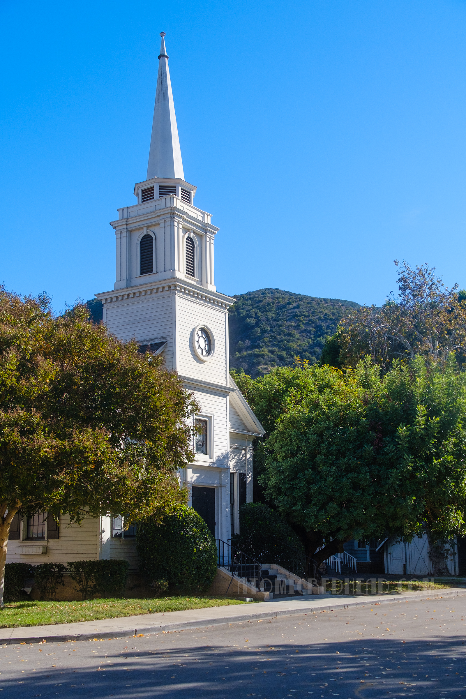 A towering white steeple church rises above parts of Midwest Street.