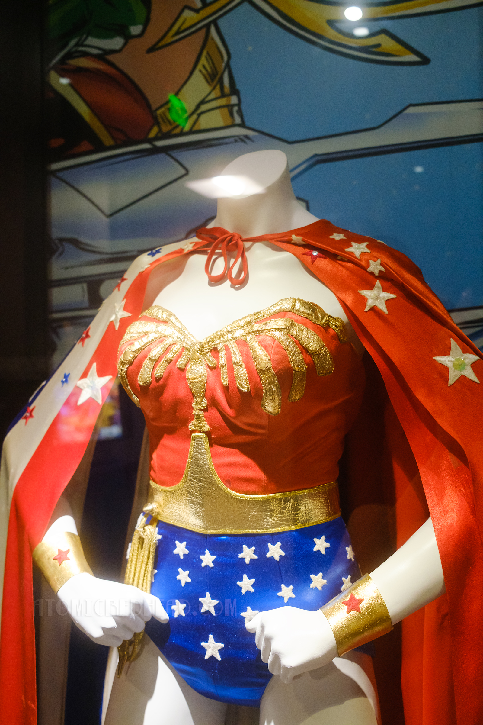 Lynda Carter's original Wonder Woman costume from the TV series, featuring a red stripe cape with stars, a red bodice with gold detail, and blue lower half with white stars.