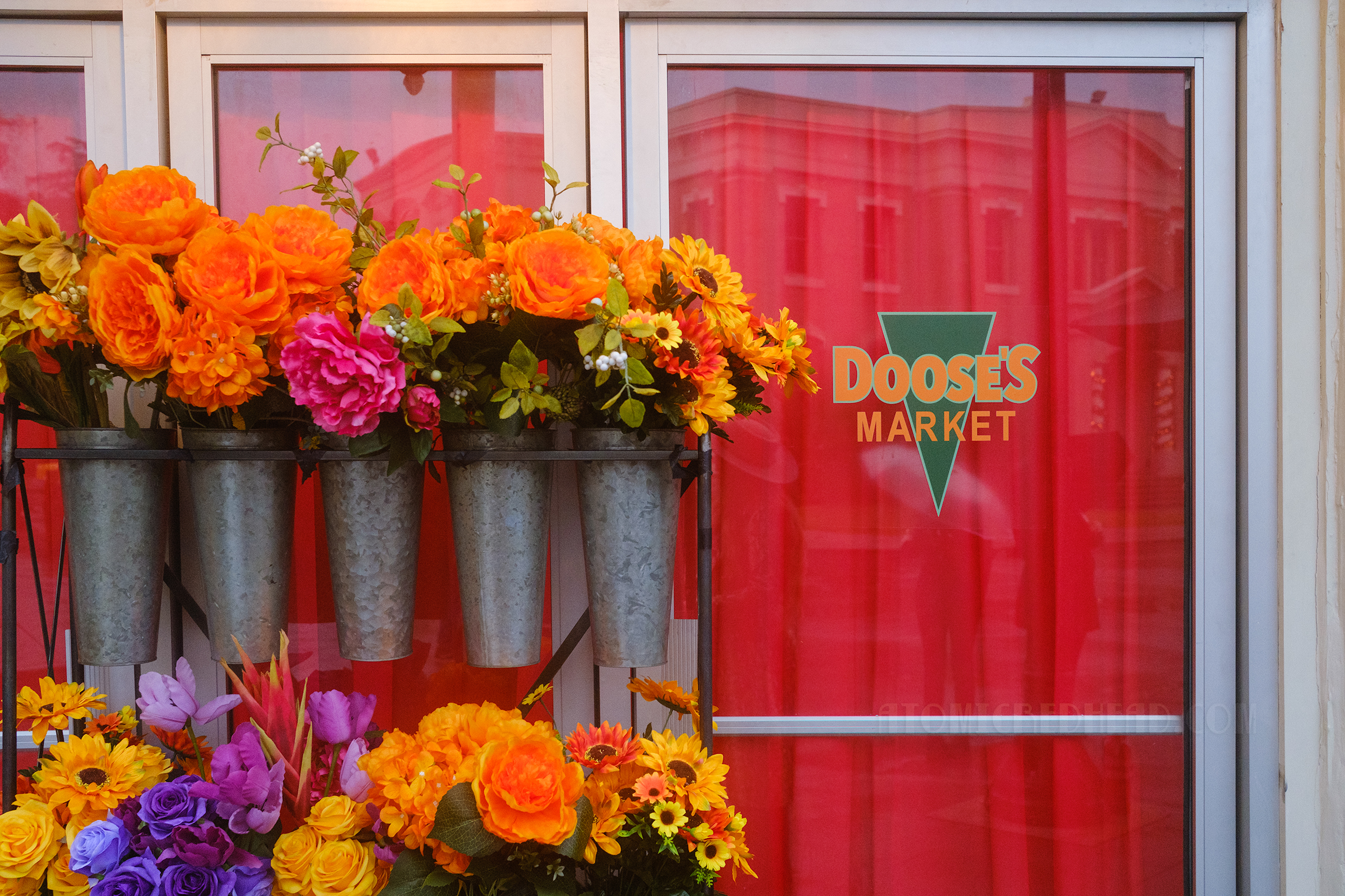 Flowers sit outside of Doose's Market, which is painted on the door.