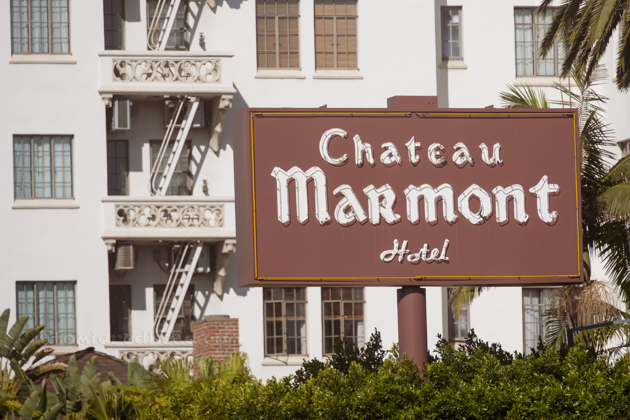 View of the neon sign reading "Chateau Marmont Hotel" which is a large brown rectangle with white gothic letters.