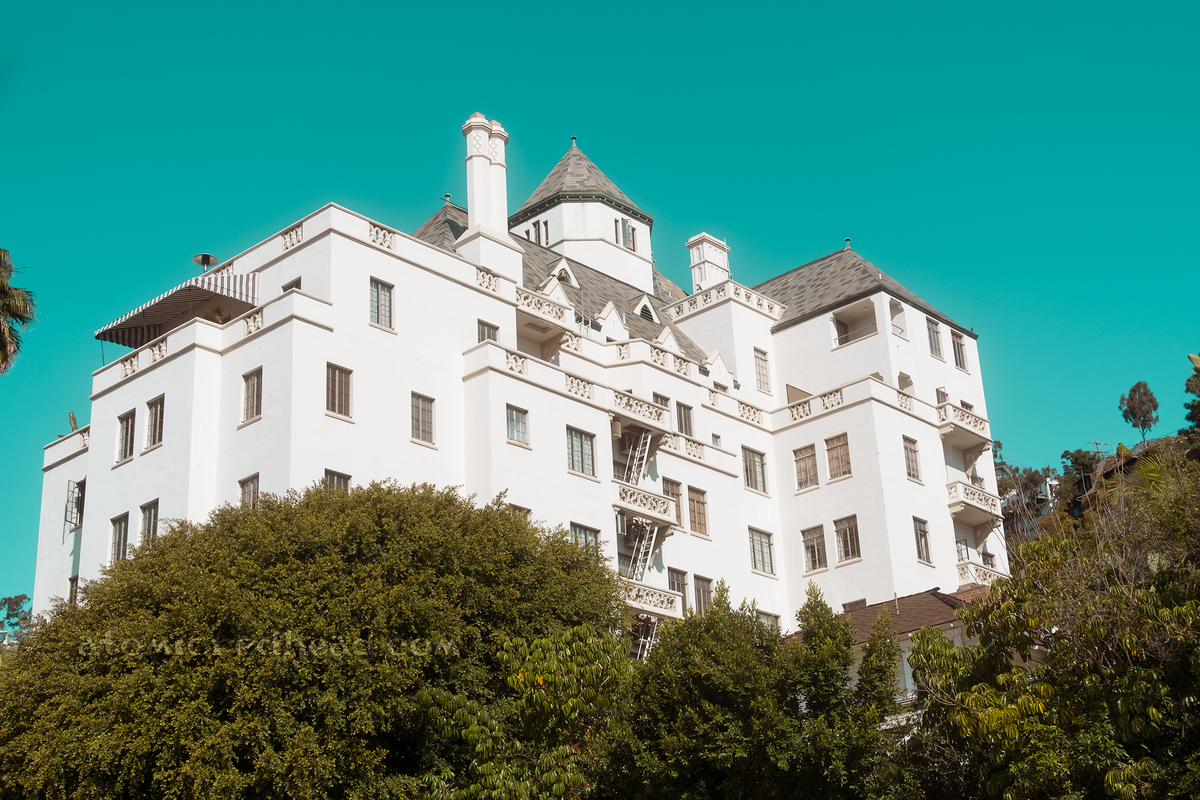Overall exterior view of the hotel, which rises from a lush green space like a French castle.