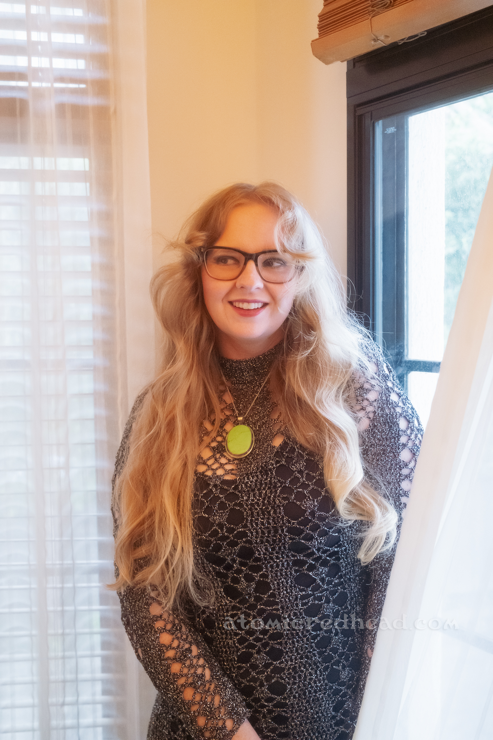 Myself, wearing a silver knit dress with a black slip underneath and a green stone necklace.