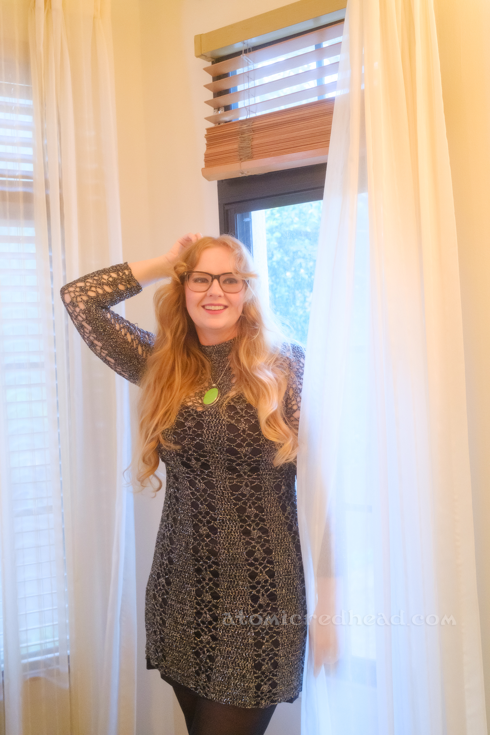 Myself, wearing a silver knit dress with a black slip underneath and a green stone necklace.