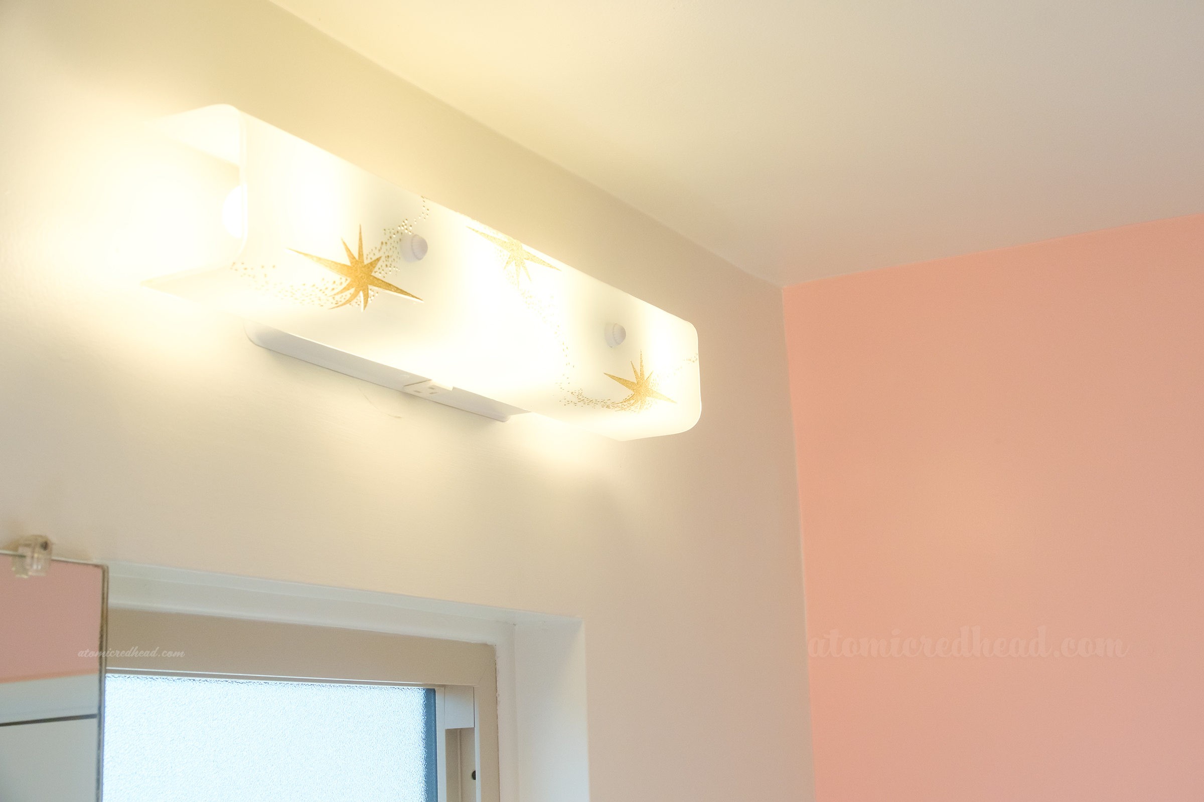 Close-up of the light fixture which is white and has small gold starbursts on it.