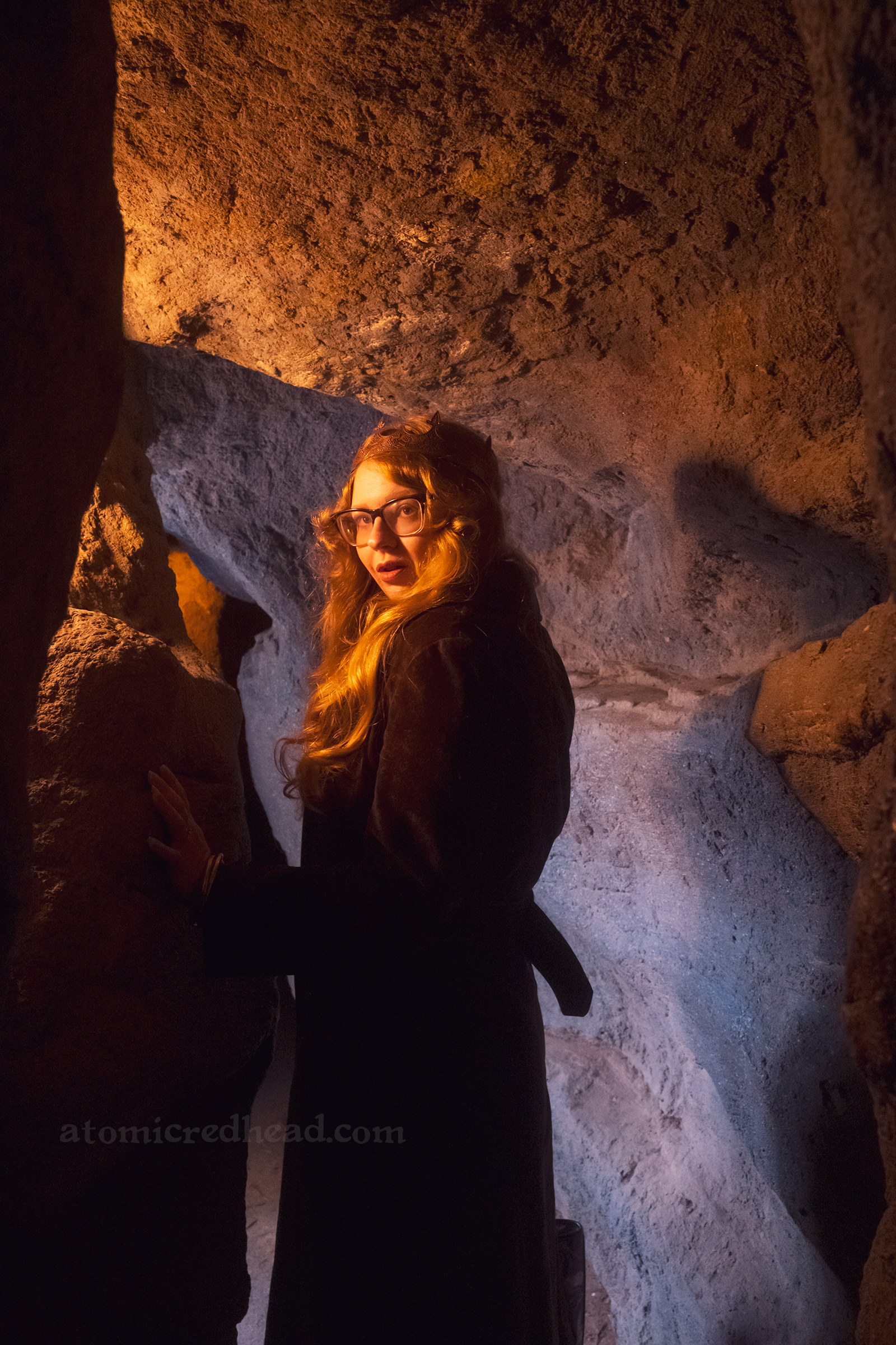 Myself standing in a cave, wearing a long brown coat and copper crown.