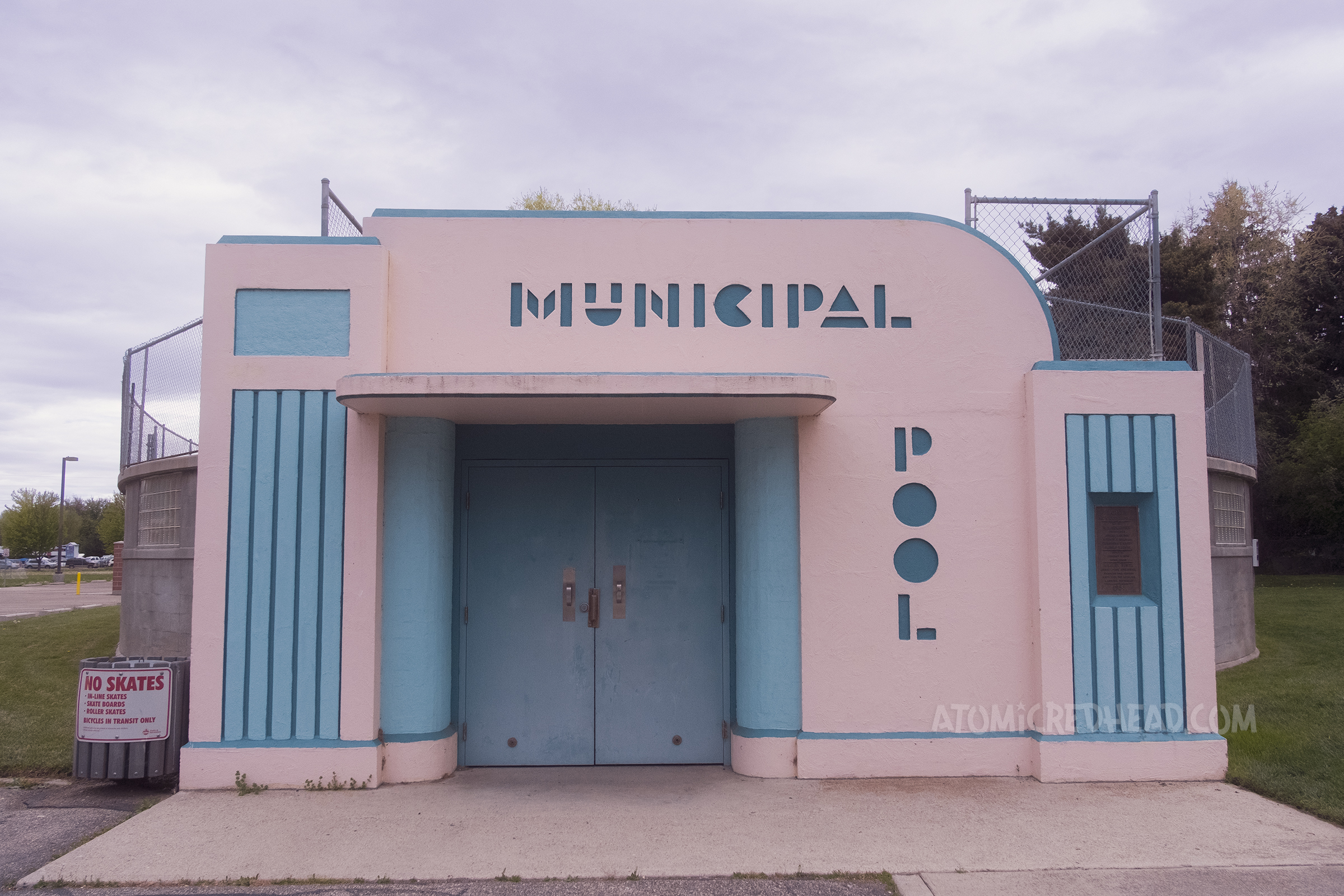 A pink and blue streamline modern doorway to a pool, in letters above the door it reads "Municipal" and to the right of the door reads "Pool"