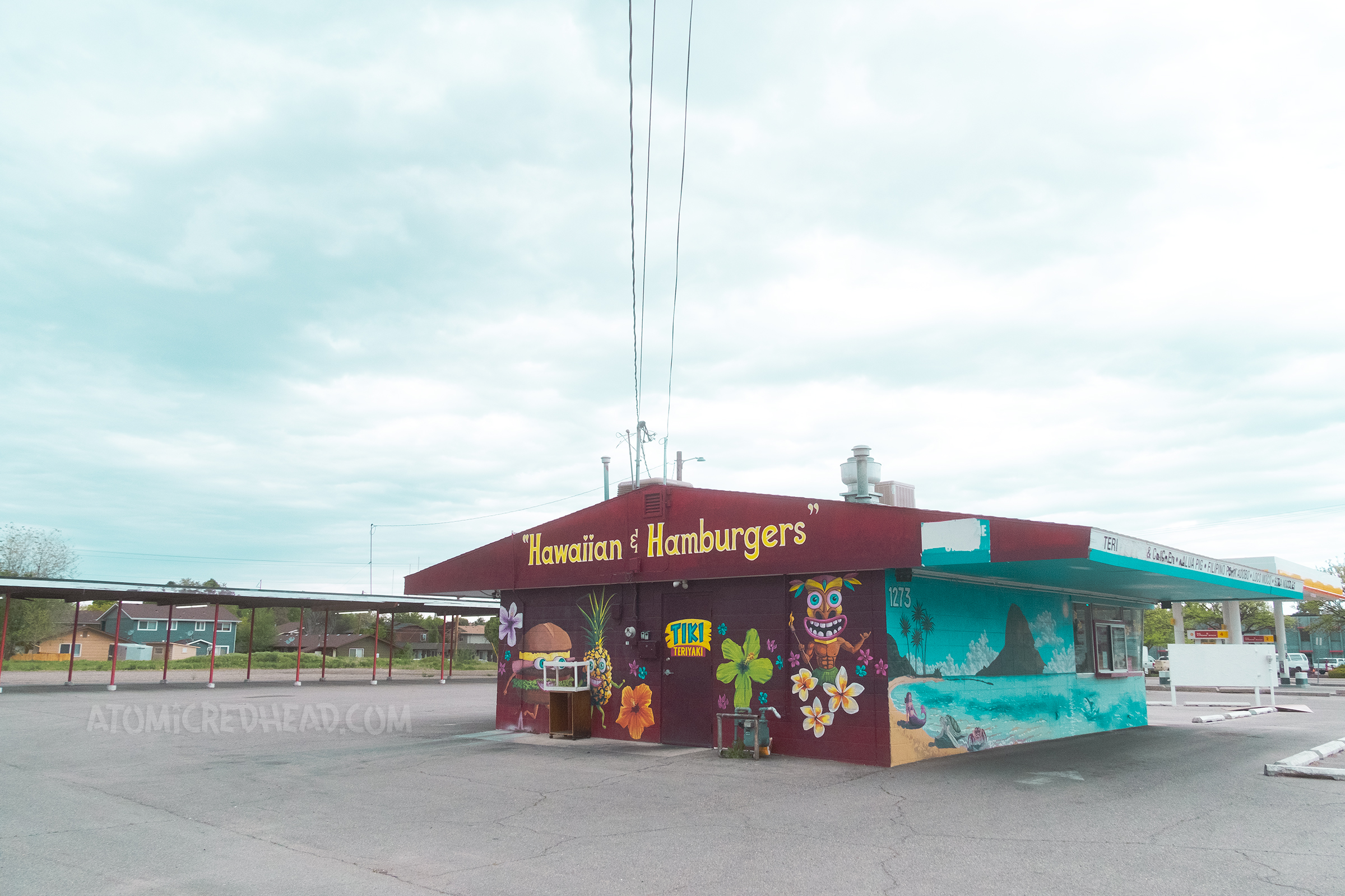 Back view of the restaurant with a mural of an ocean scene, tiki, and burger.