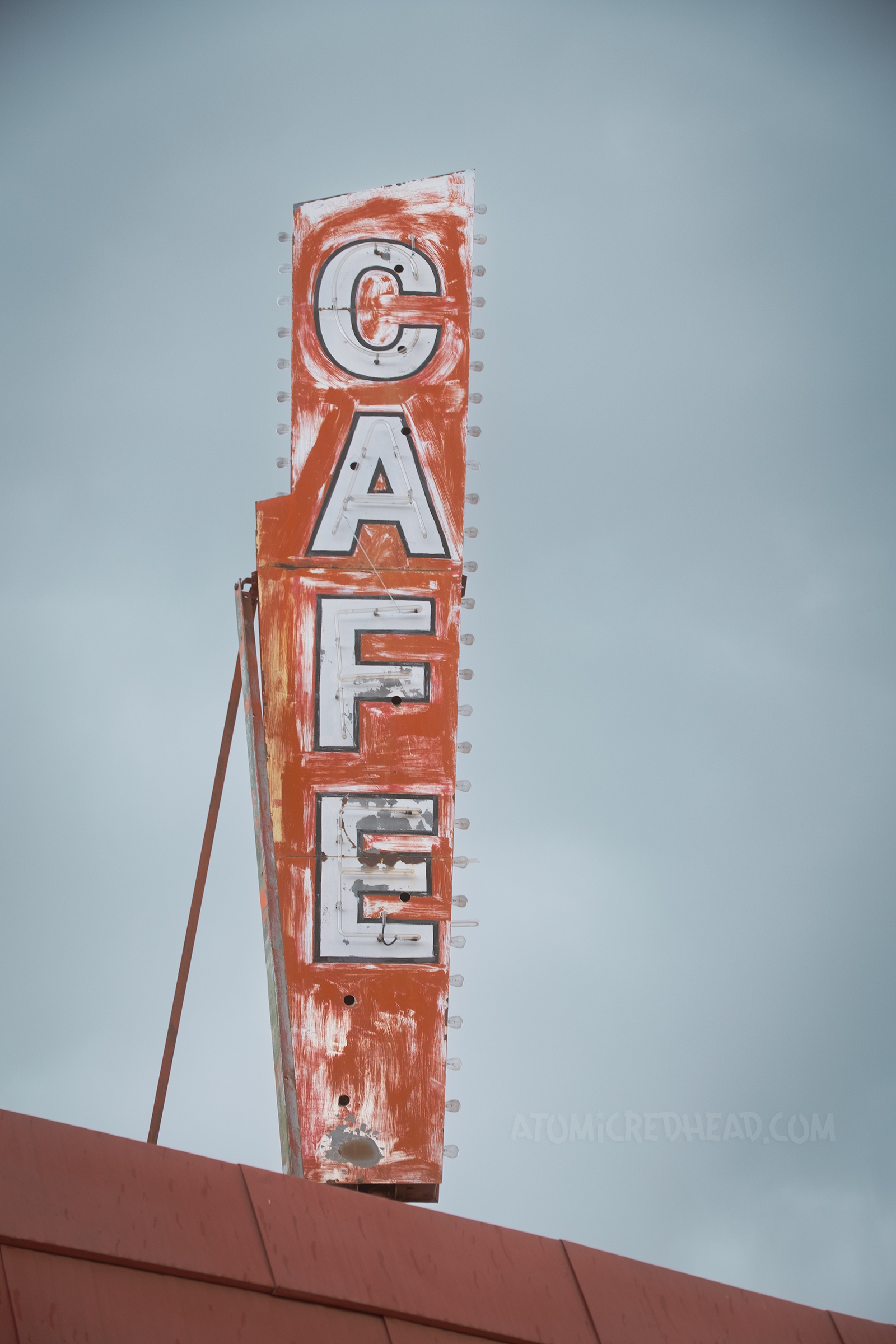A faded red and white sign reads "Cafe" in neon.