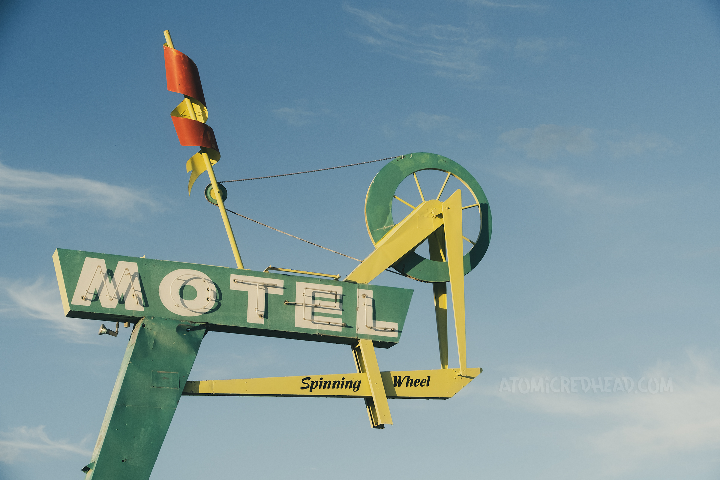 A sign made in the shape of a spinning wheel reads "Motel" in neon through the middle.