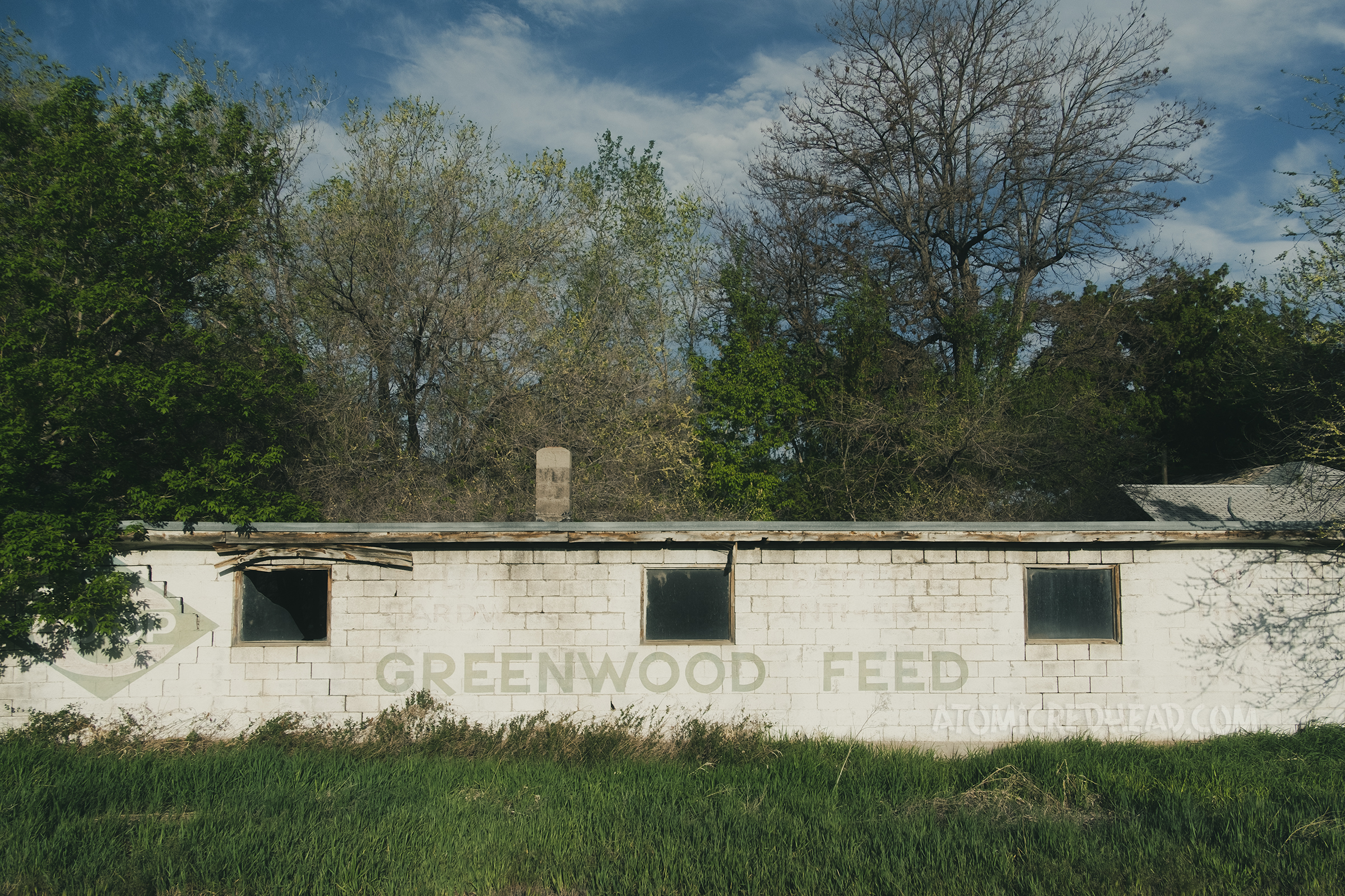 A large abandoned building reads "Greenwood Feed" in fading green letters.