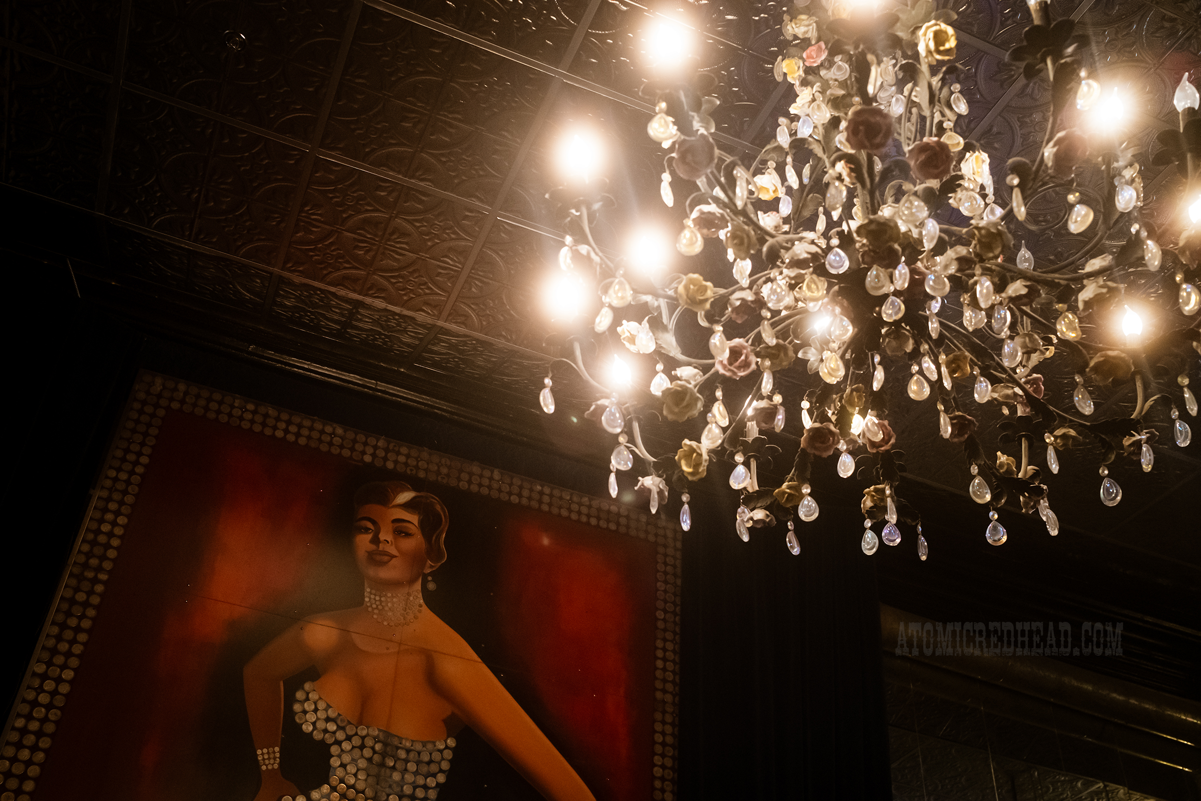 A large crystal chandelier hangs in the upper right and in the background on the left is the portrait of the silver queen.