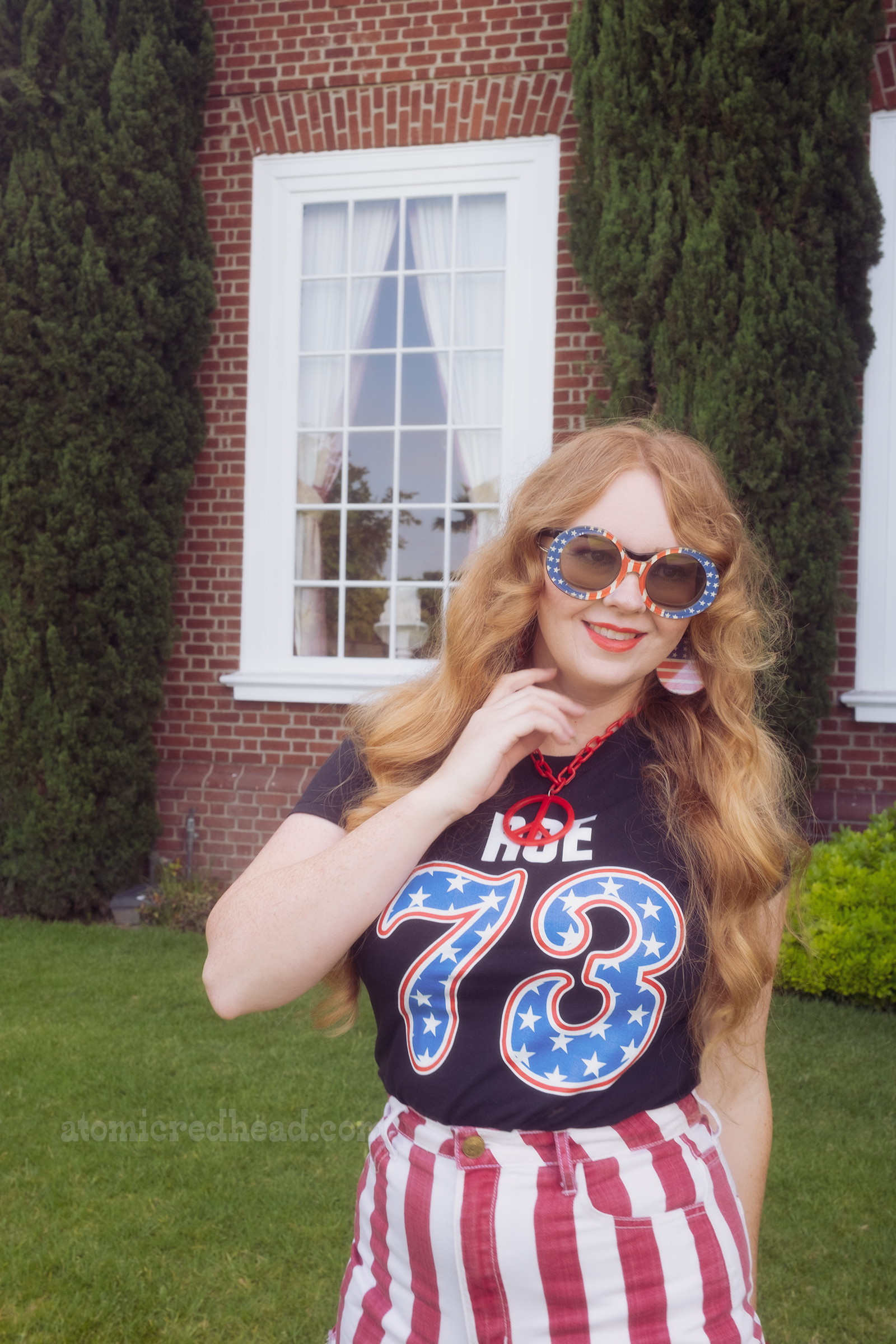 Myself, wearing sunglasses that feature the American Flag, a black shirt reading "Roe 73" with the "73" in blue with white stars, edged in red, a red and white stripe shorts, standing in front of Independence Hall.