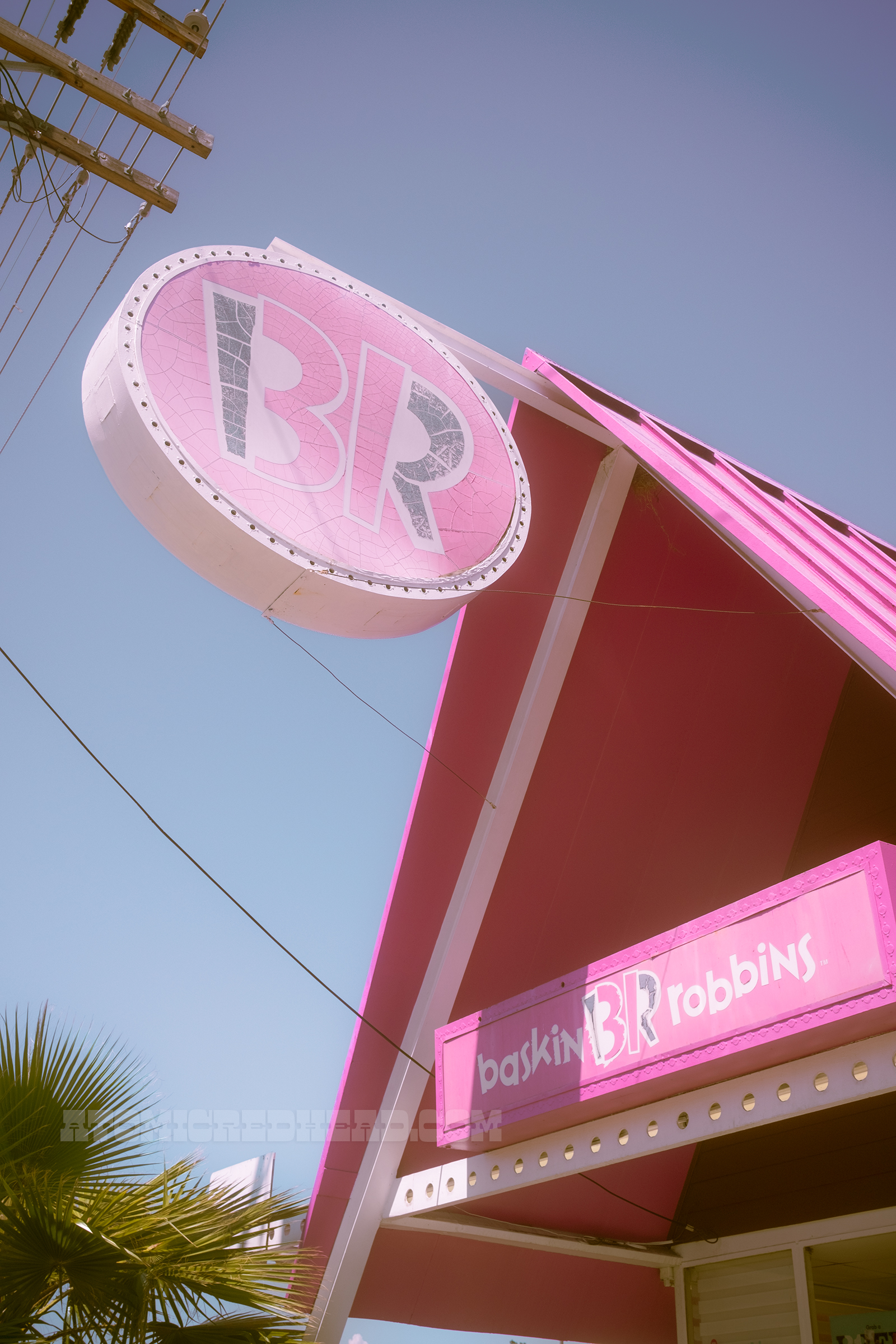 Angled view of the front, which features a large rectangular pink sign reading "Baskin Robbins" and a large circular sign coming from the top of the roof reading "BR"