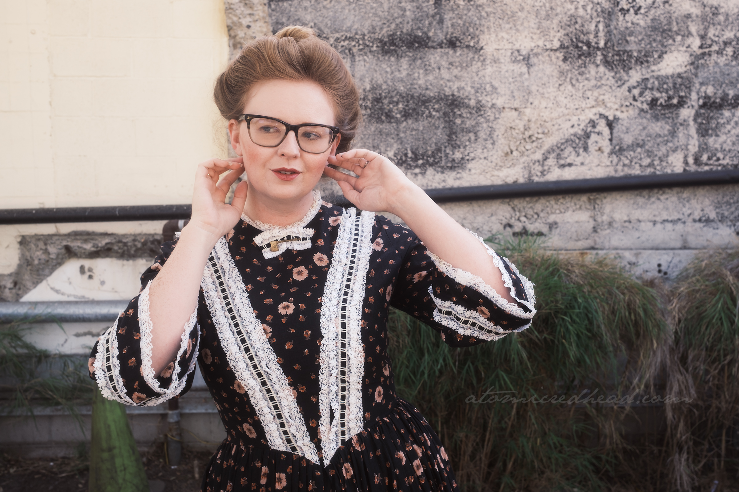 Myself, wearing a black dress with white lace trim, at the collar, a small gold hatchet brooch.