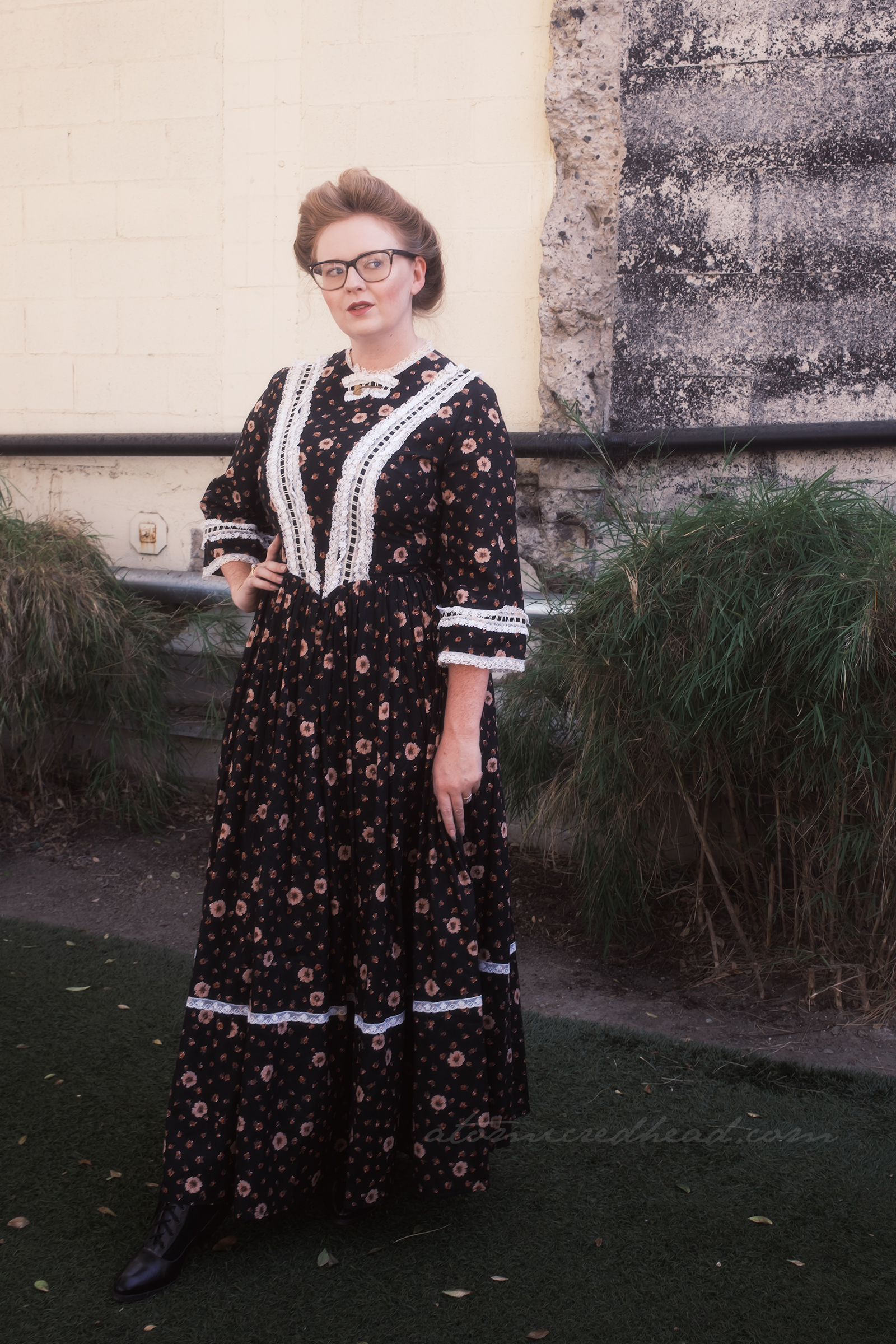 Myself, wearing a black dress with white lace trim, at the collar, a small gold hatchet brooch.