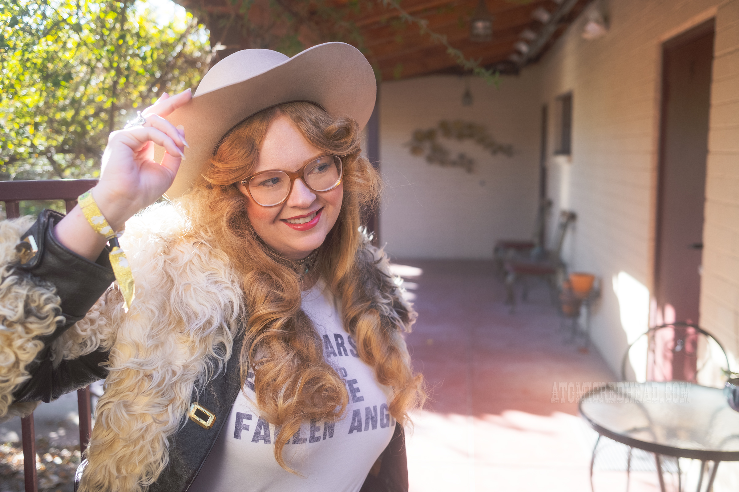 Myself, wearing a cream cowboy hat, a short jacket of cream and brown fur, a white tee reading "Gram Parsons and the Fallen Angels" in blue letters, and blue jeans.