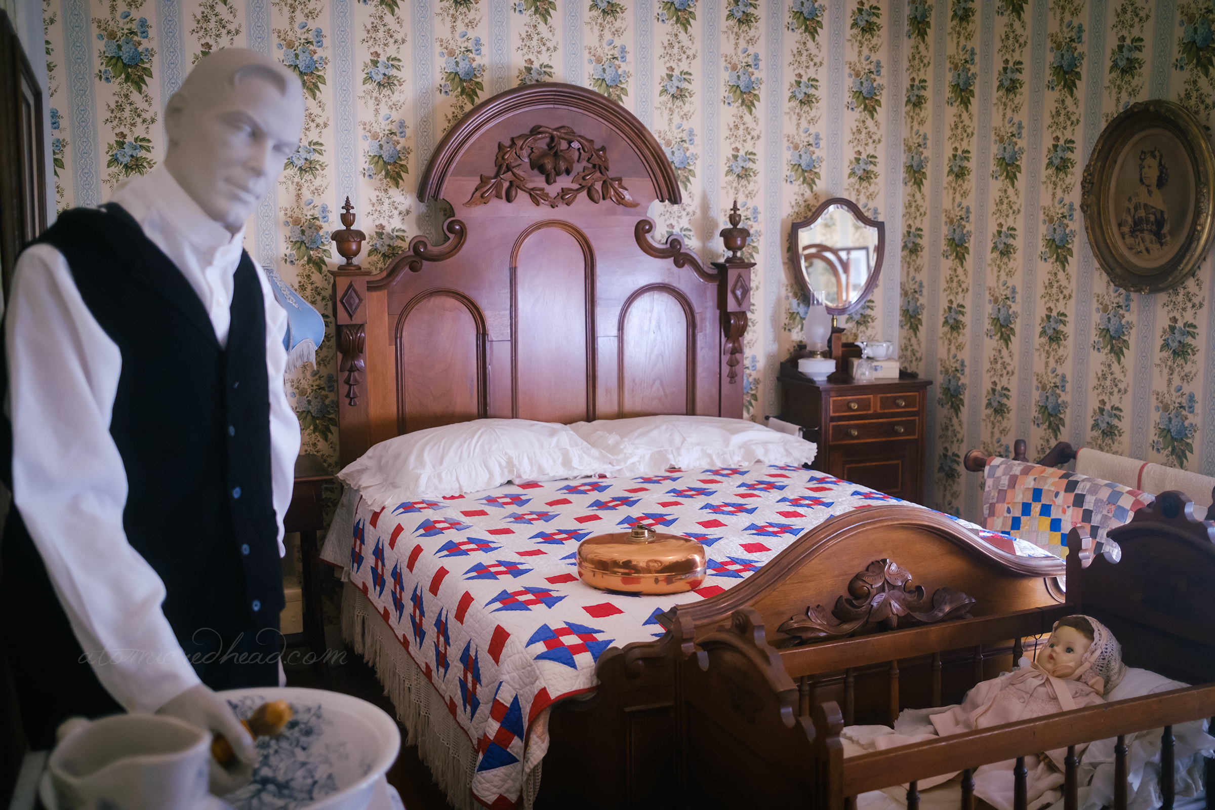 A large carved wood bed with a quilt on it.