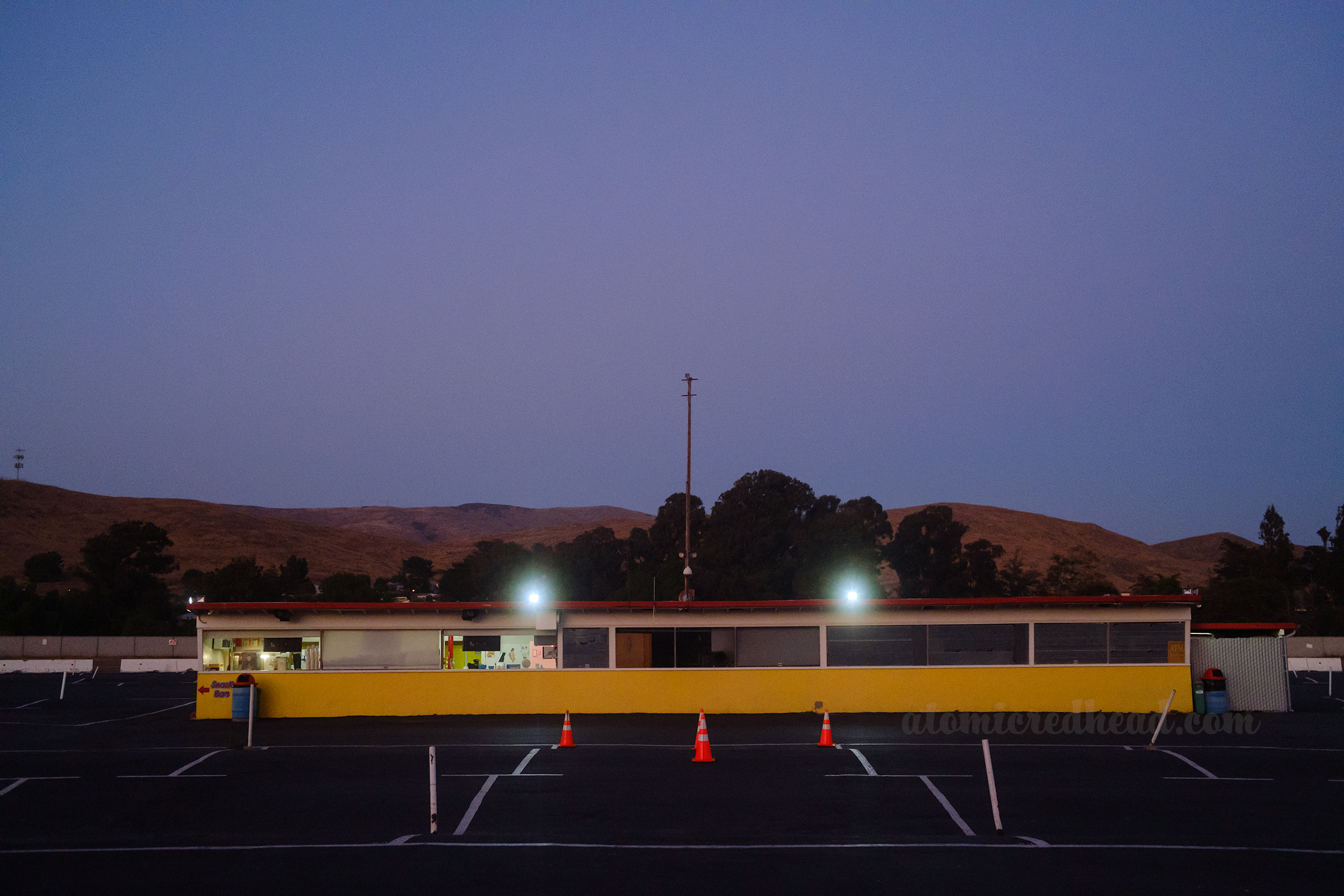 View of the long and low concession stand, painted yellow with a red roof.
