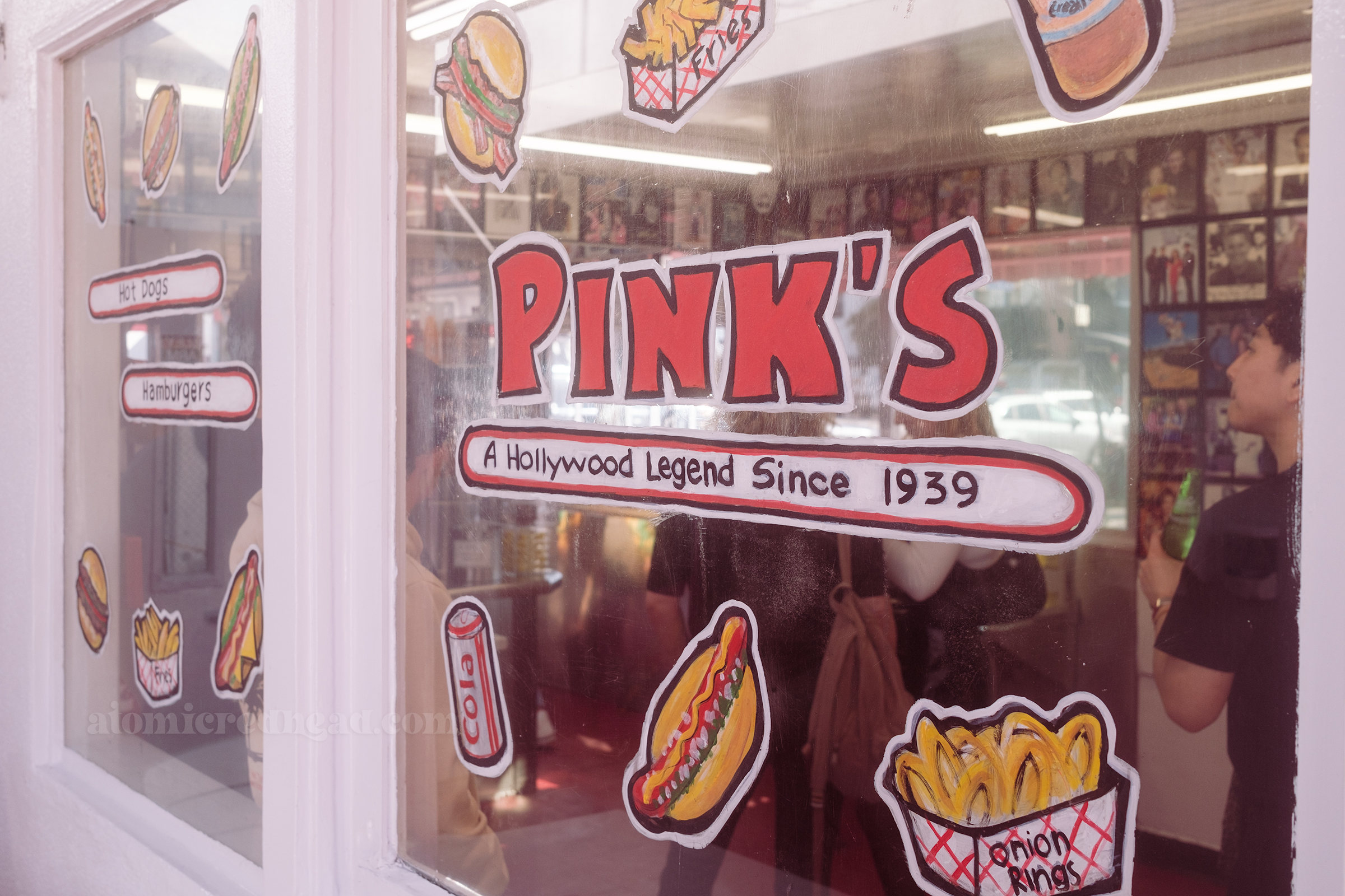 A window is painted with various food items and reads "Pink's A Hollywood Legend Since 1939"