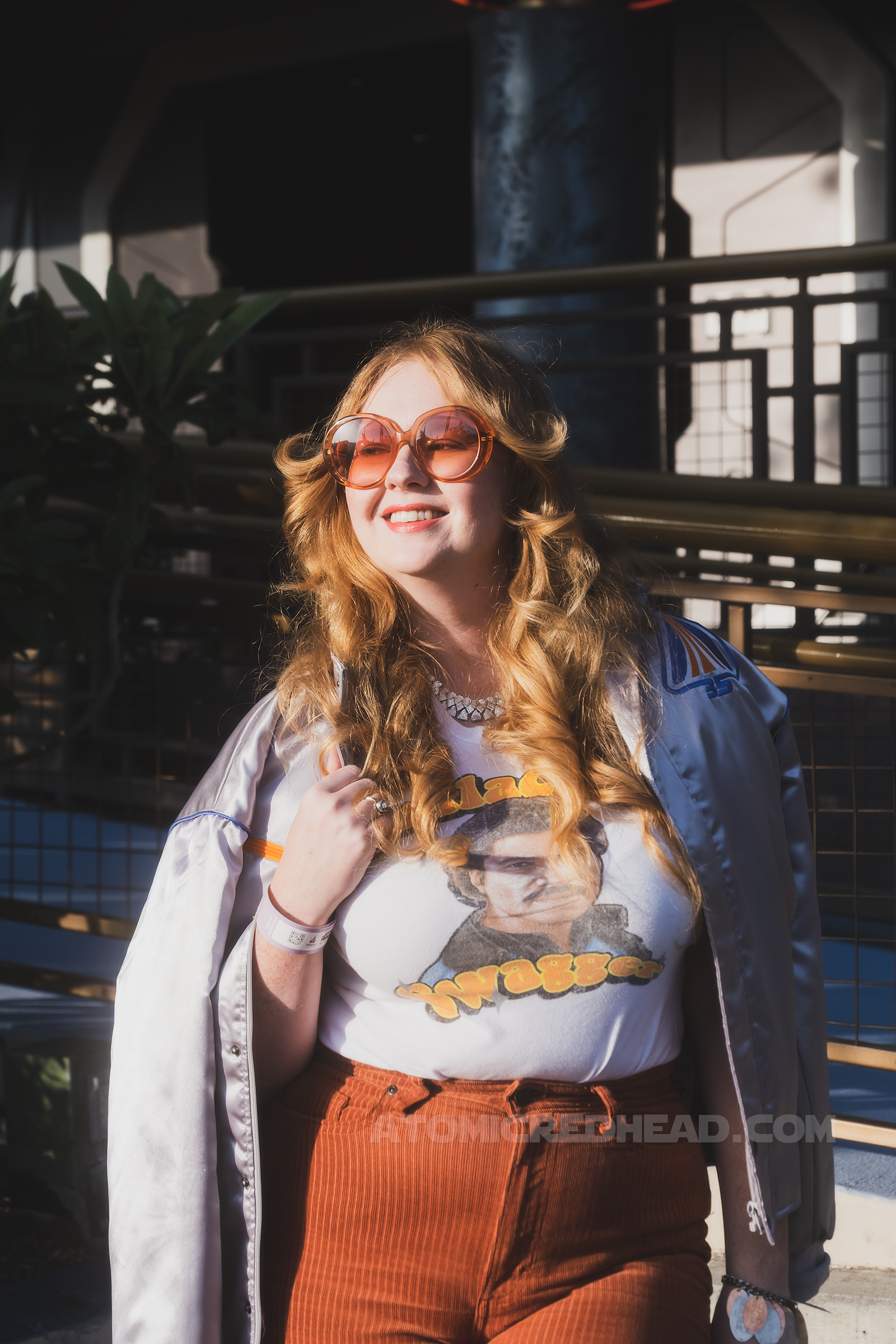 Myself, standing in Tomorrowland, wearing a silver jacket, a white tee featuring Lando reading "Galactic Swagger" and brown corduroy pants.