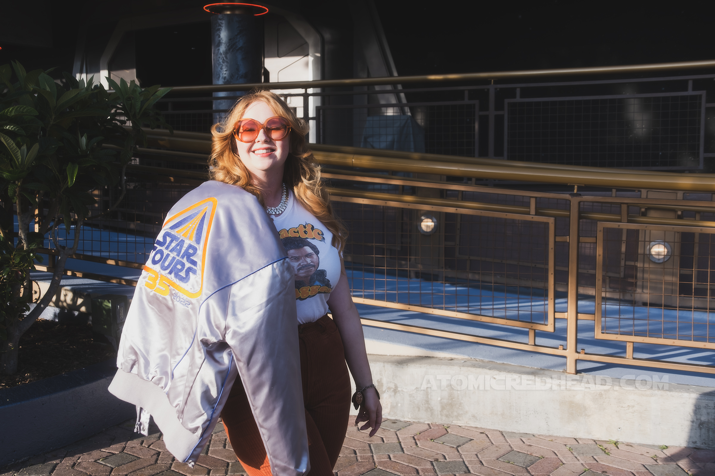 Myself, standing in Tomorrowland, with a silver jacket over my shoulder. On the back of the jacket "Star Tours 35 1987 2022" is embroidered in blue and orange."