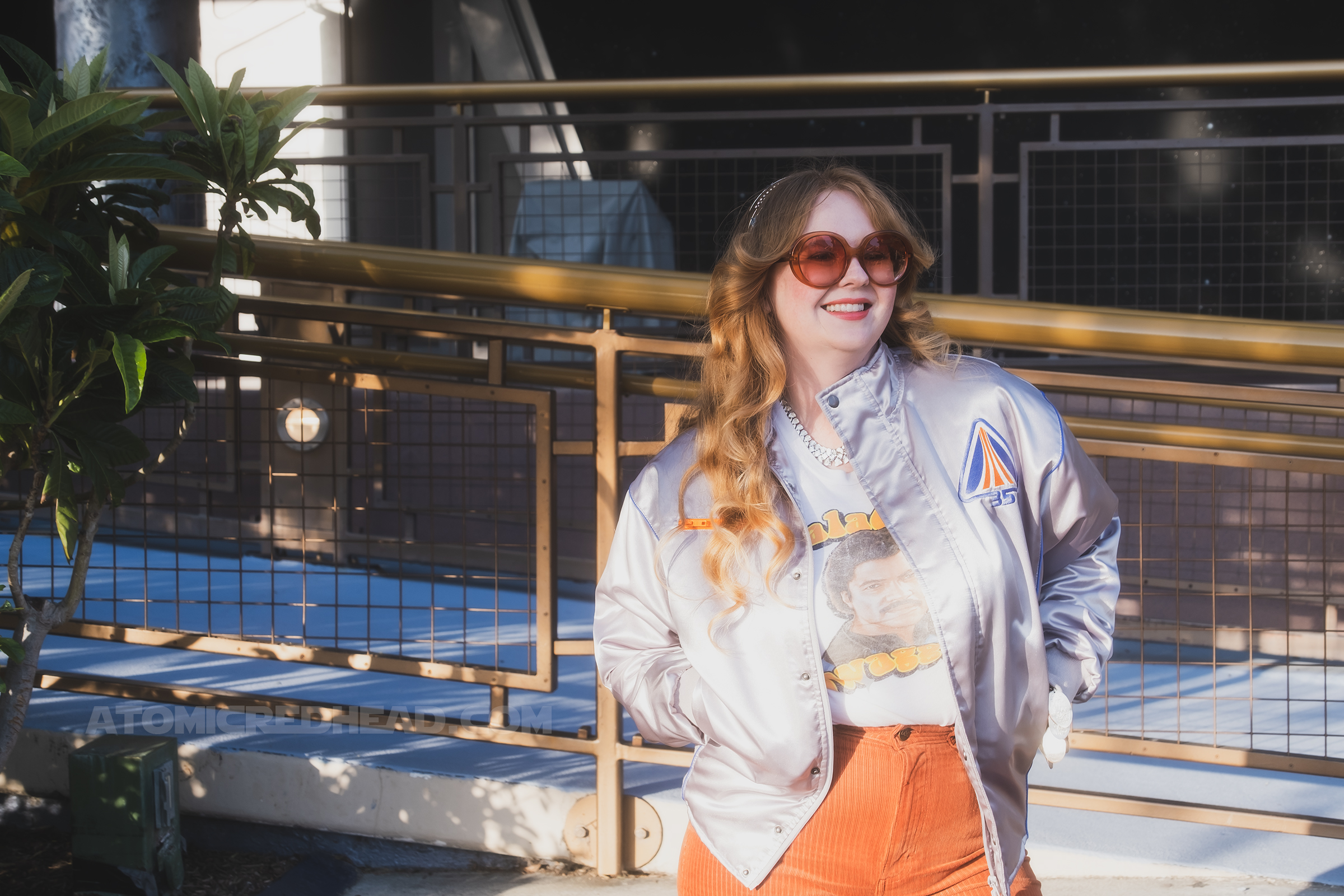 Myself, standing in Tomorrowland, wearing a silver jacket, a white tee featuring Lando reading "Galactic Swagger" and brown corduroy pants.