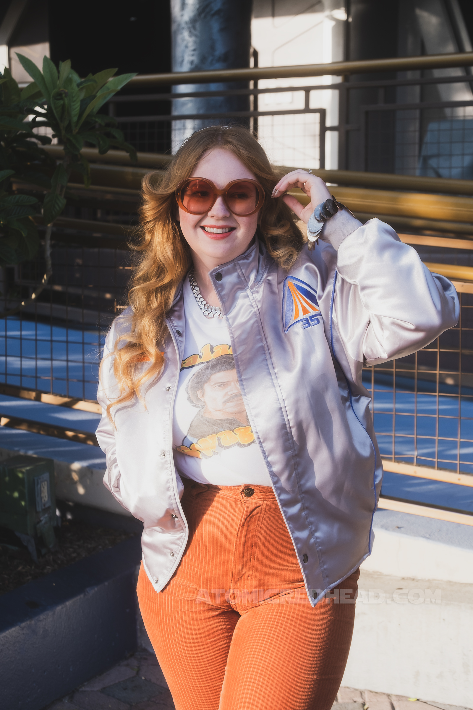 Myself, standing in Tomorrowland, wearing a silver jacket, a white tee featuring Lando reading "Galactic Swagger" and brown corduroy pants.