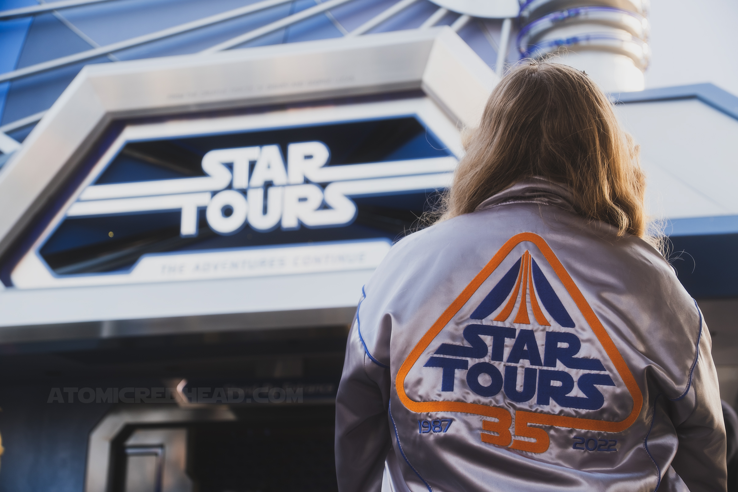 Back view of myself wearing the Star Tours jacket with the attraction sign in the background.