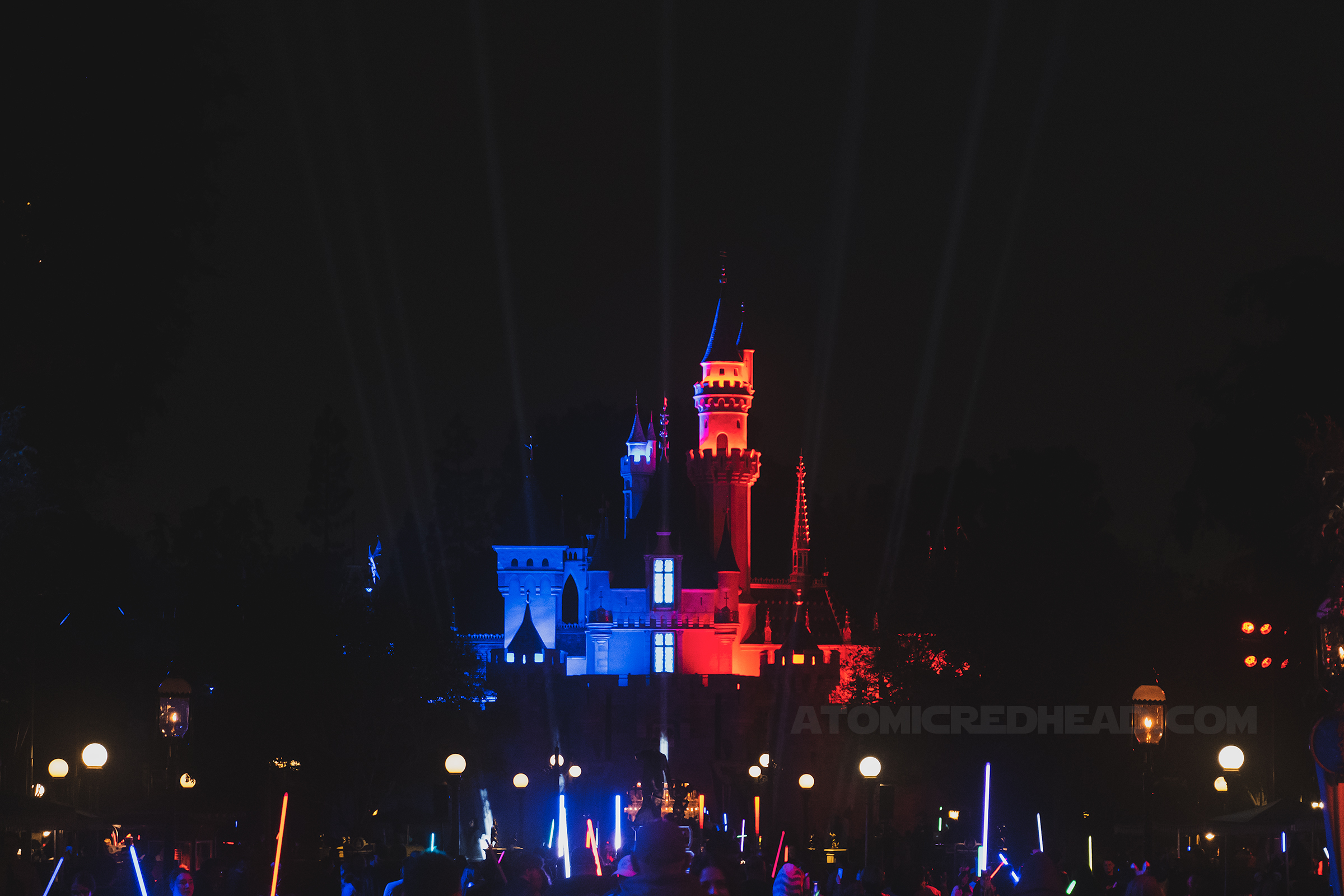Sleeping Beauty Castle lit up in half blue and half red light to symbolize the Rebellion and the Empire.