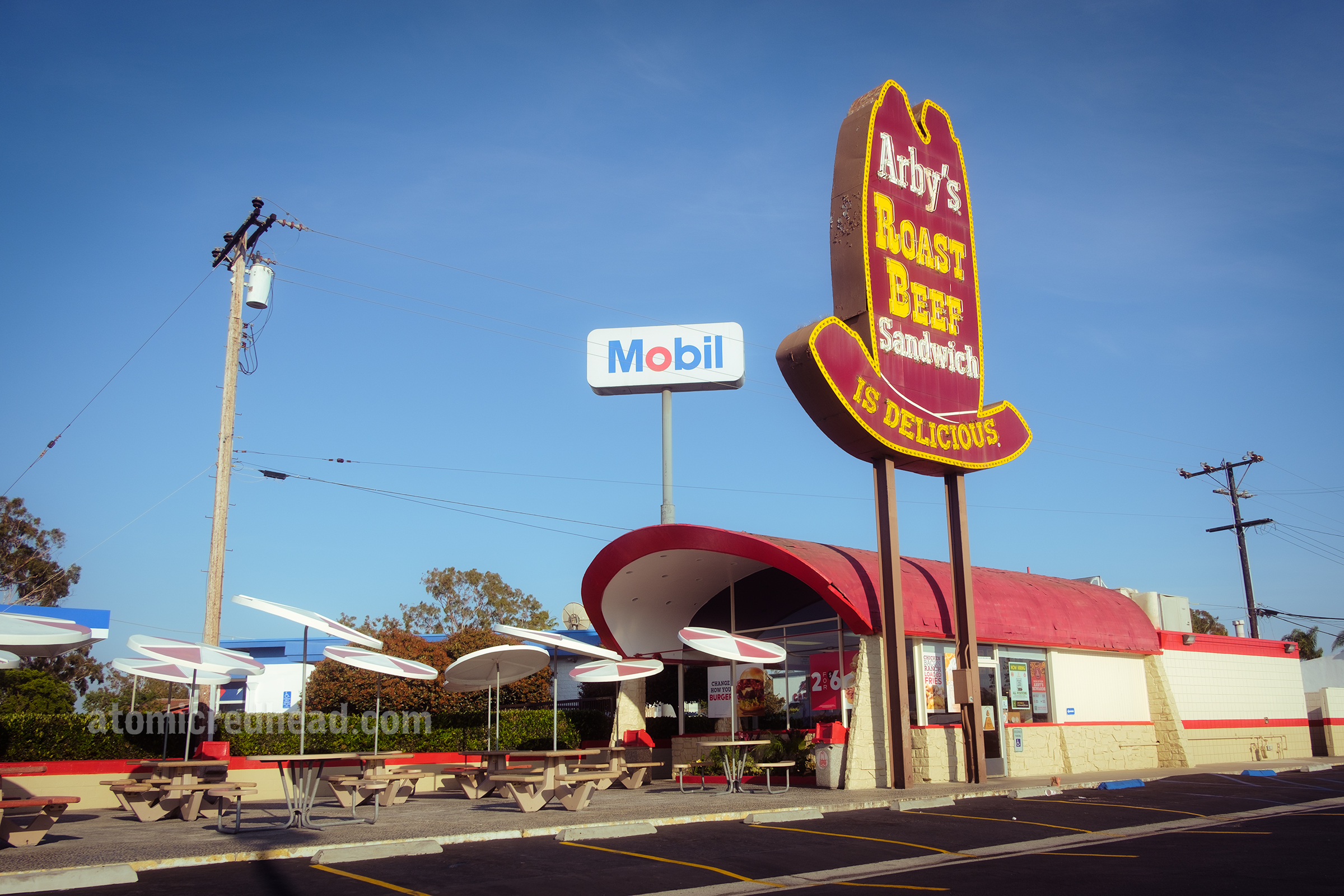 Overall view of the restaurant, with the towering sign, covered wagon style building and patio seating.