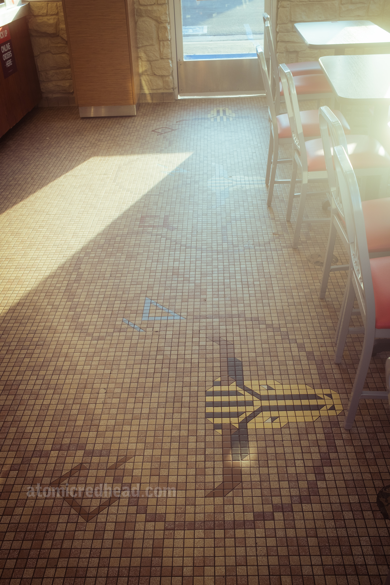 Small tiles create a mosaic image of steer heads across the floor of the restaurant, a looping rope connects them and a scattering of brands tie it together with a western theme.