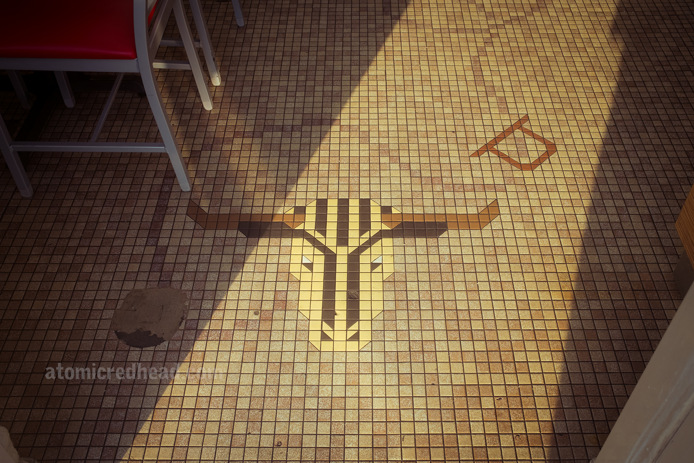 The sun shines in on the small tiles that create a mosaic image of steer heads across the floor of the restaurant, a looping rope connects them and a scattering of brands tie it together with a western theme.